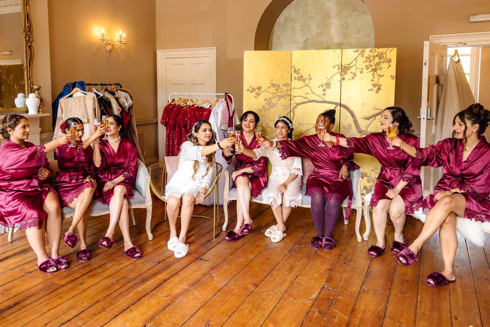 Bride and bridesmaids in red robes relaxing together during morning preparations