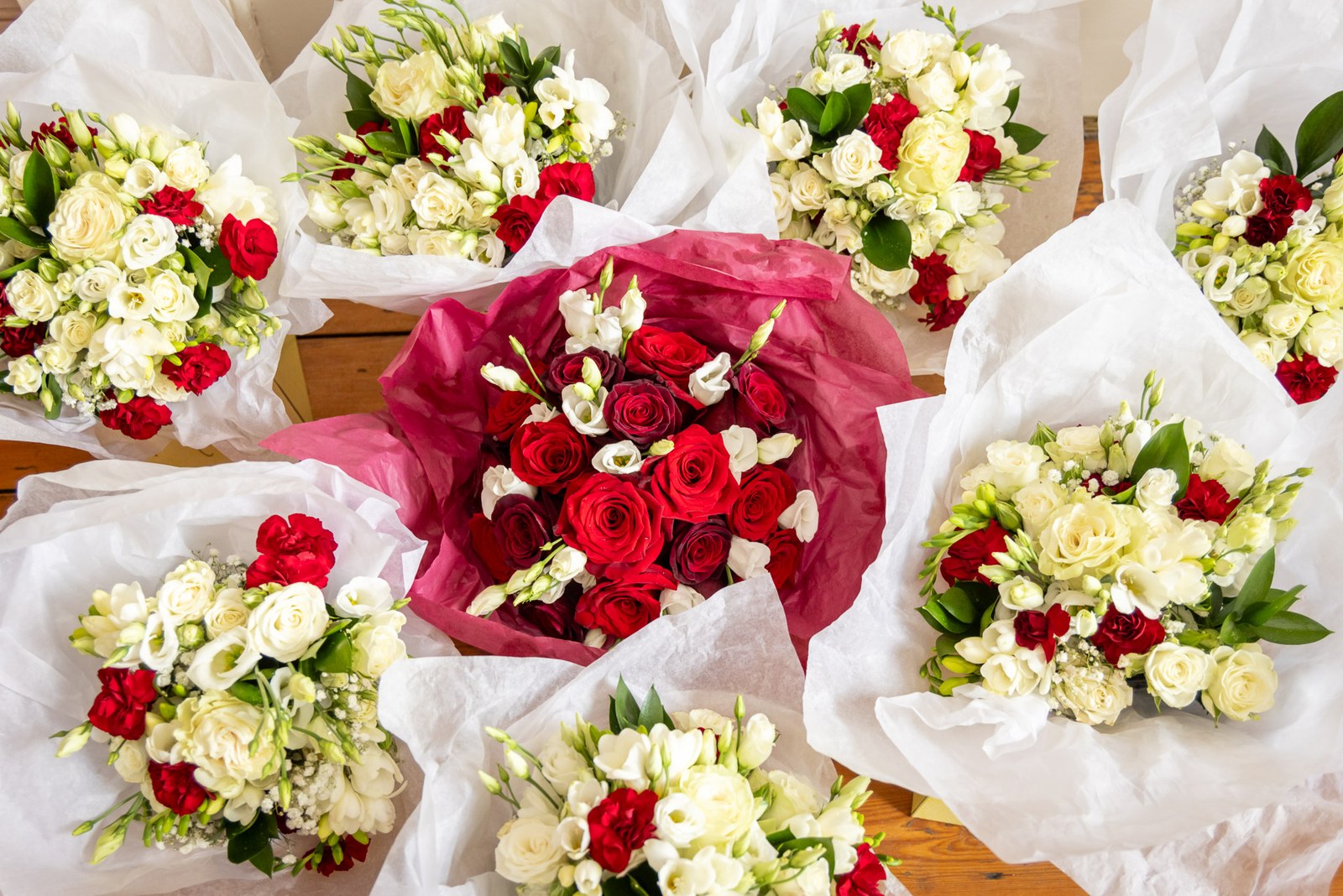 Flat-lay of red-and-white rose bouquets wrapped in tissue paper