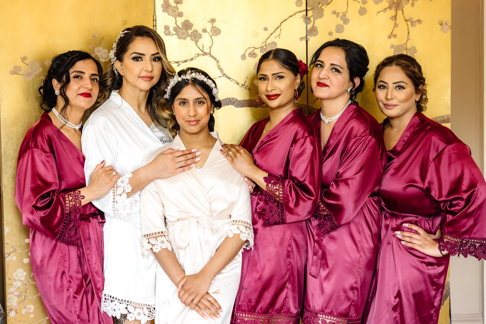 The bride with her bridesmaids and flower girl before the gold oriental screen