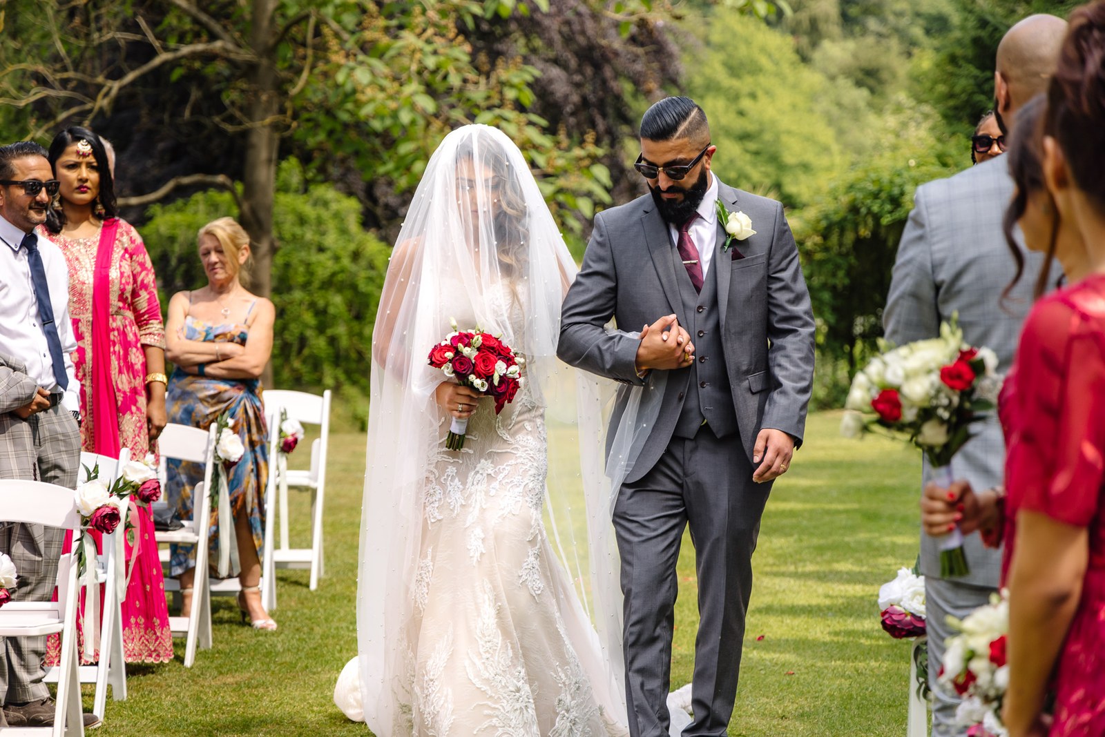 Bride walking the outdoor aisle on a relative's arm past seated guests