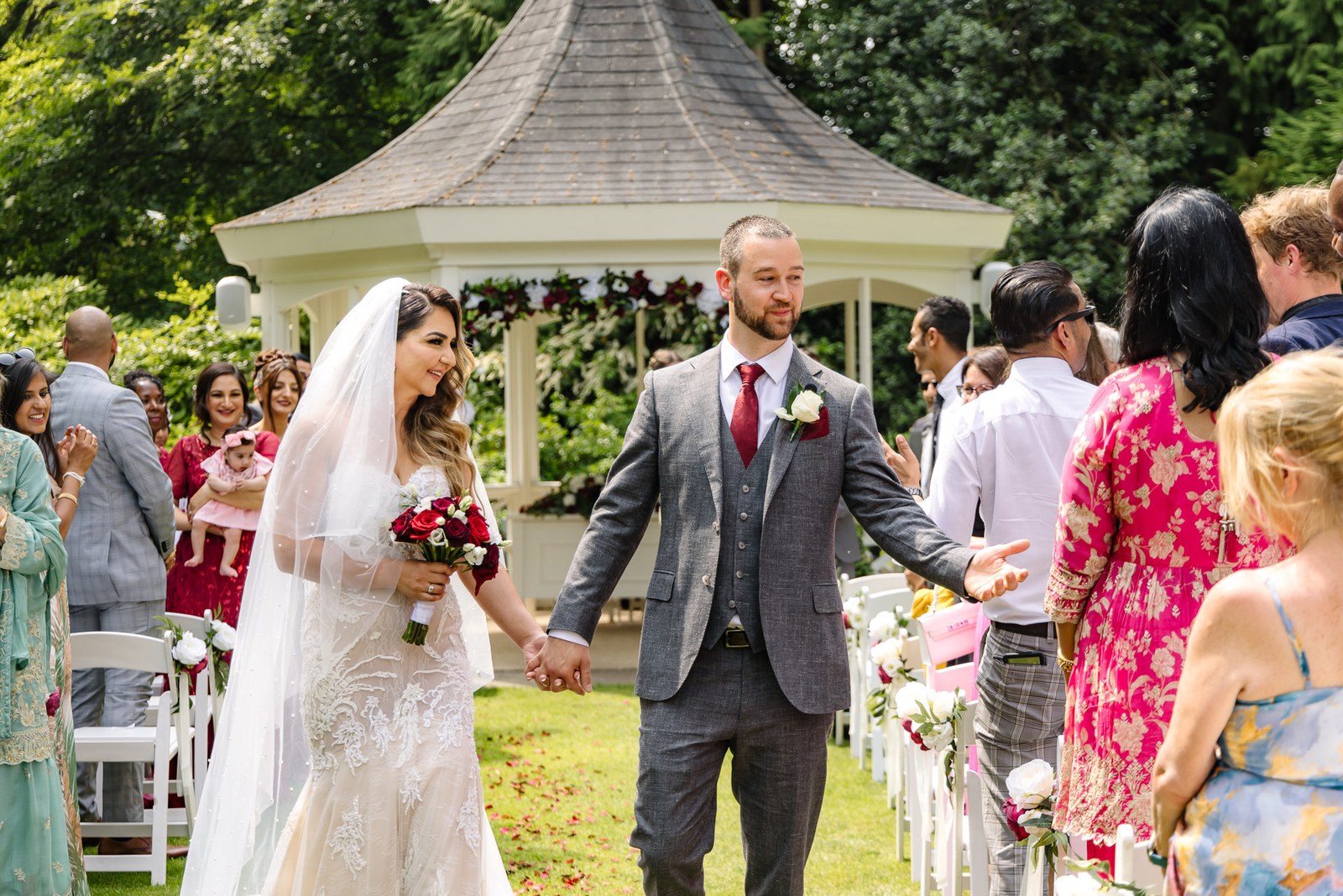 The newlyweds walk back down the outdoor aisle as guests cheer