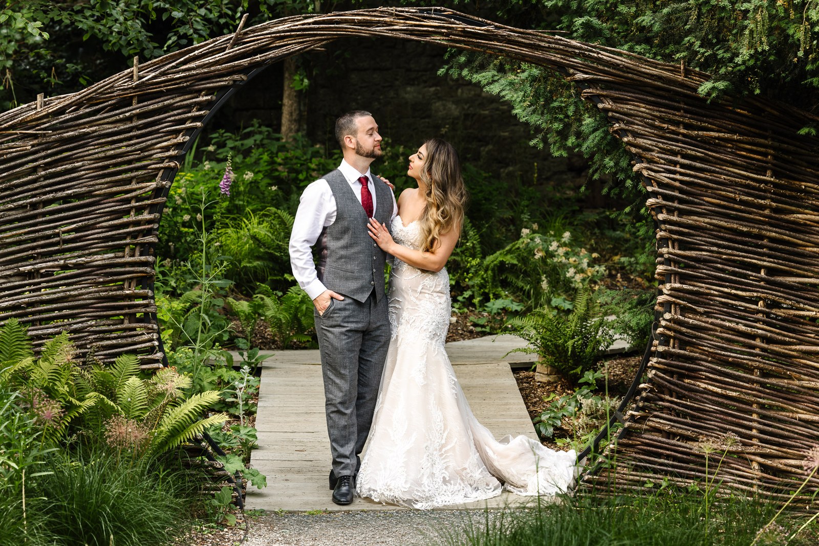 The couple embrace beneath a woven willow archway in the garden