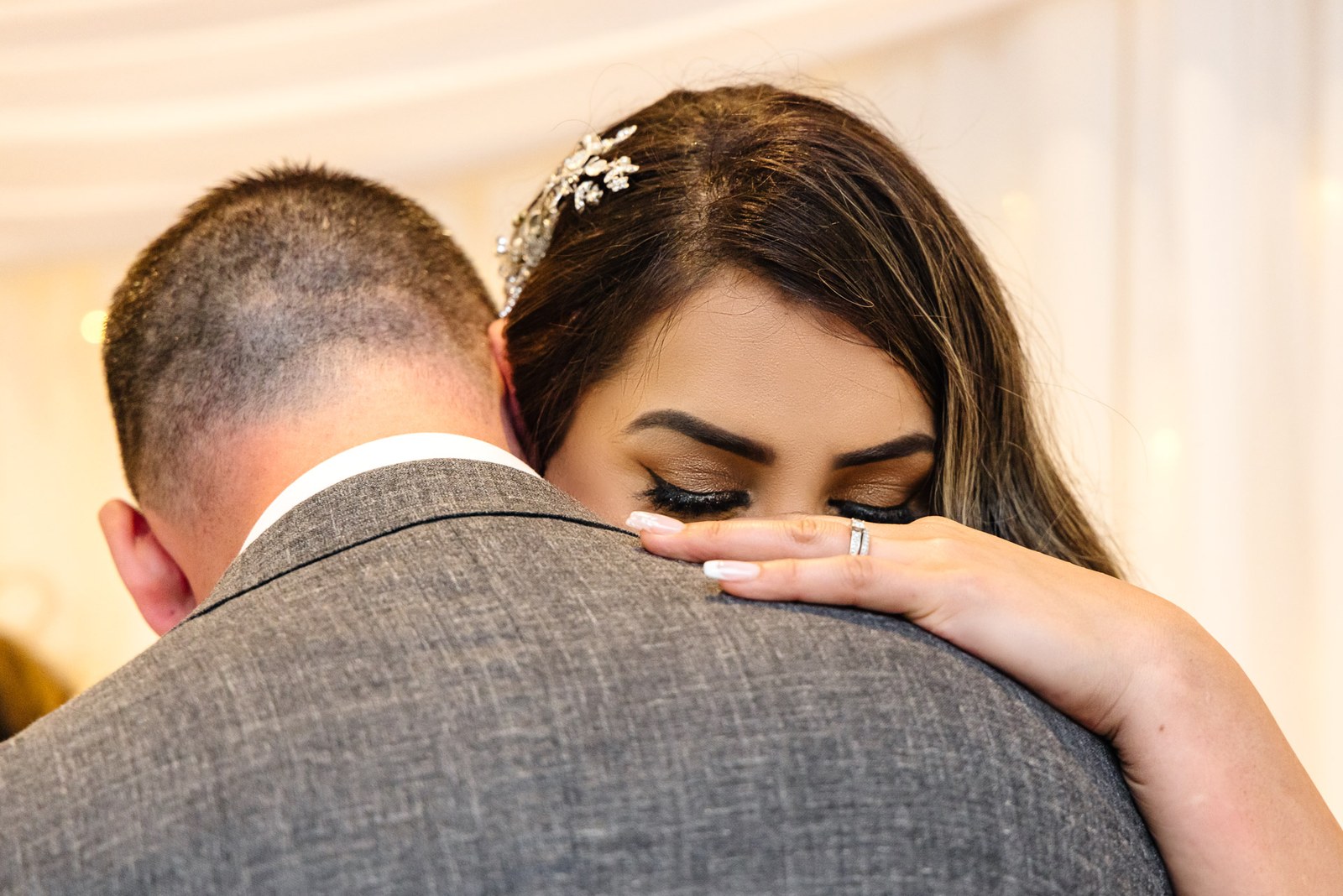 The bride embraces the groom, her wedding ring visible on his shoulder