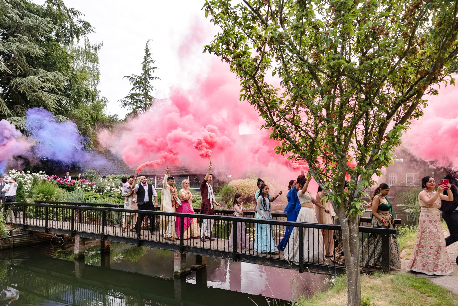 Guests set off pink and purple smoke flares on the bridge over the lake