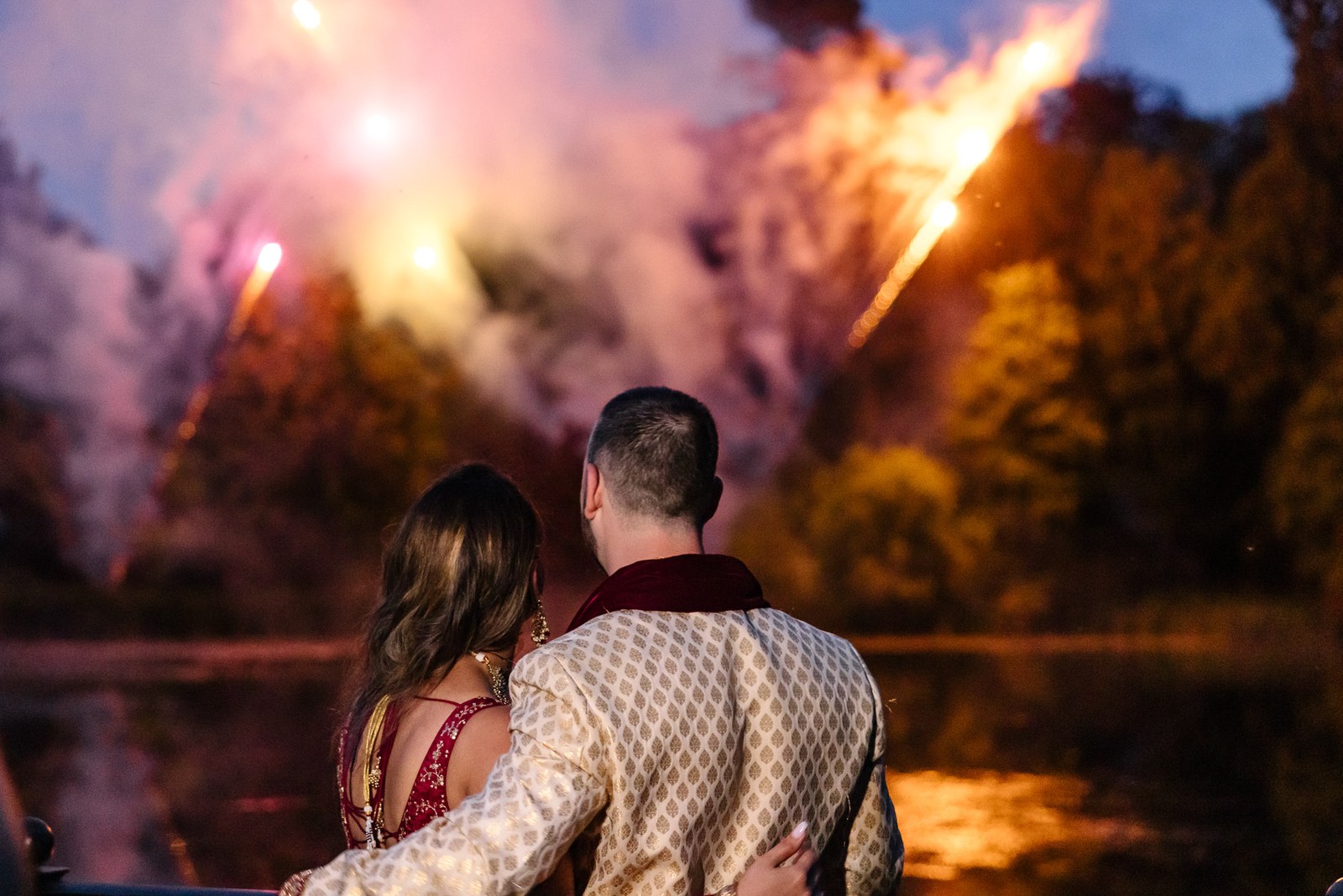 The couple watch fireworks burst over the lake at night