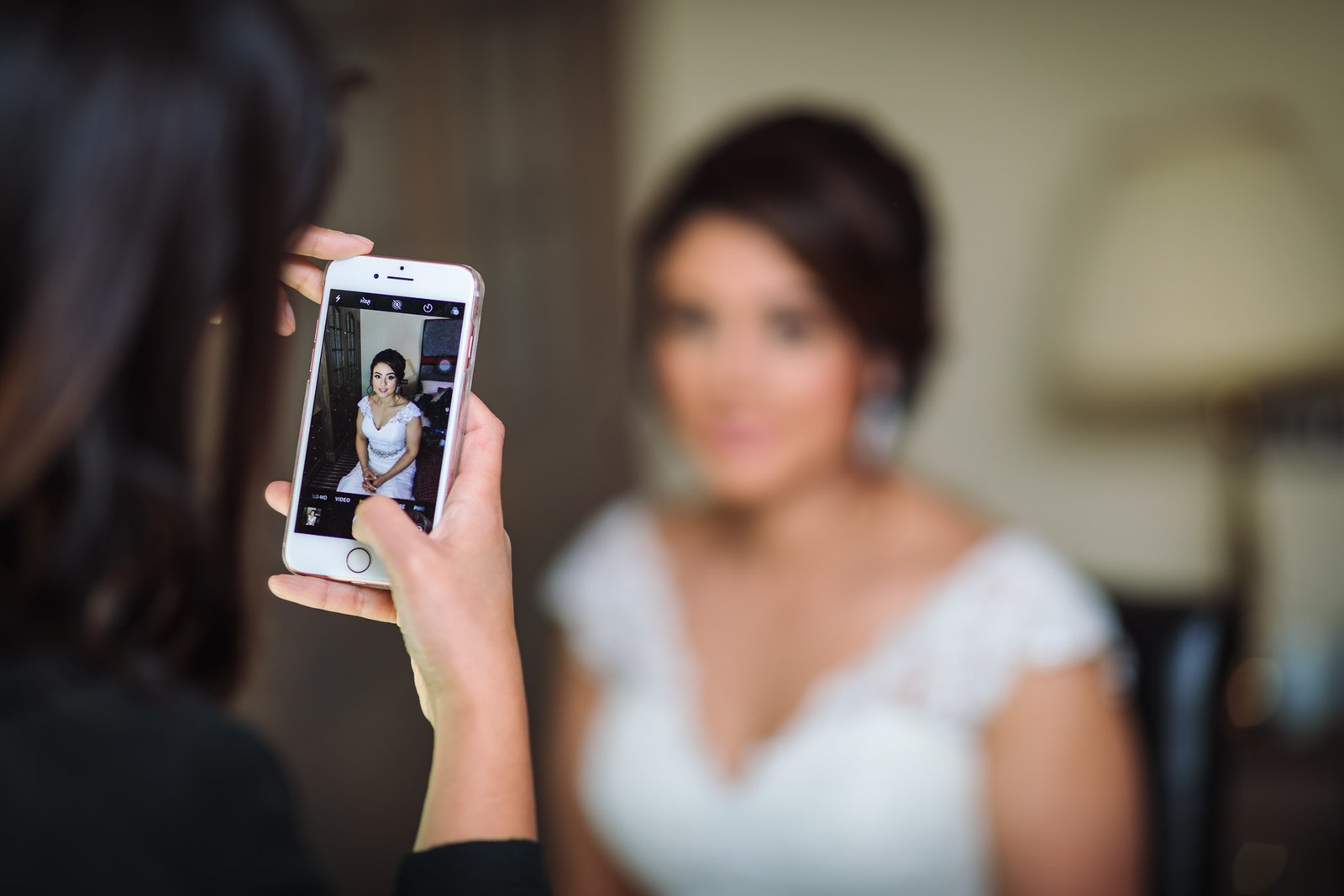 A guest photographing the bride on a phone during the final preparations