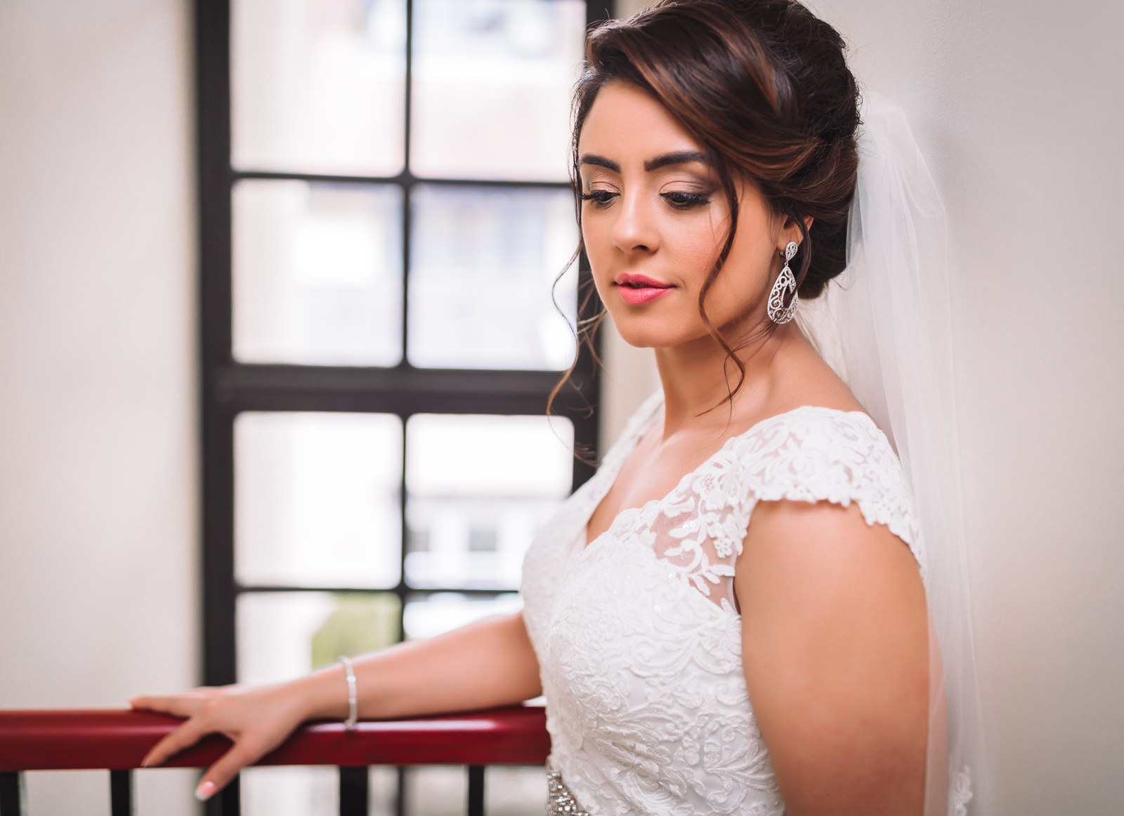 The bride resting on a red rail beside the tall Crittall windows of Villiers Hotel
