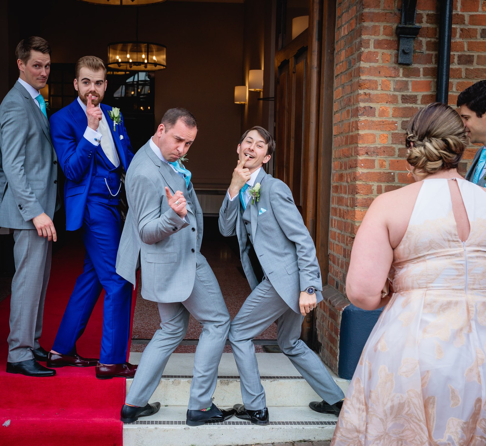 The groom and groomsmen larking about on the red-carpeted steps at Villiers Hotel