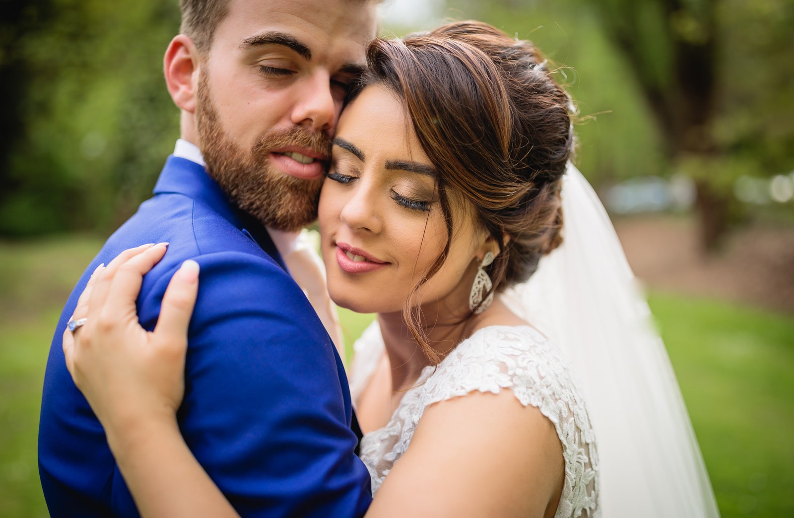 Close-up of the couple cheek to cheek, the groom in a royal blue suit