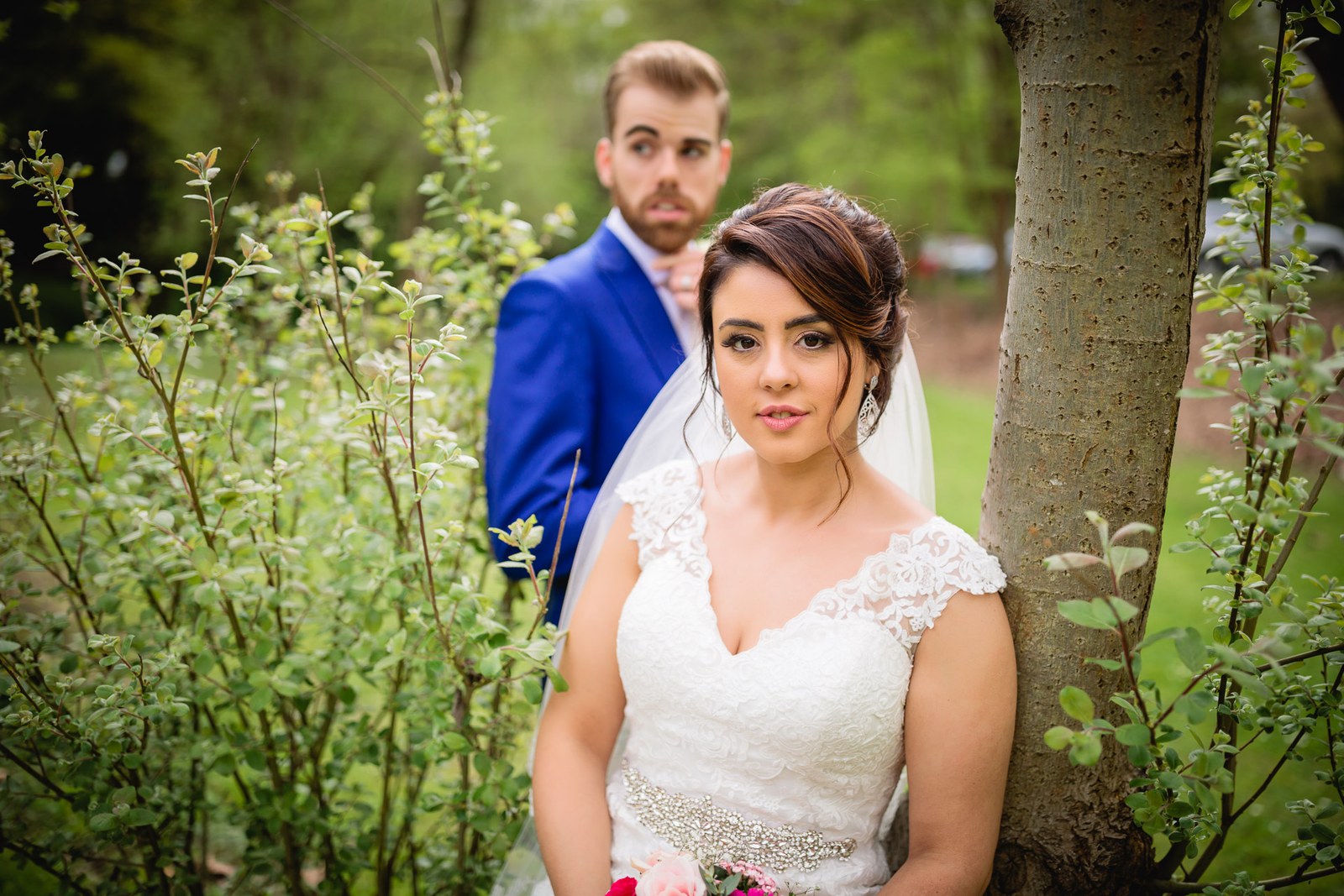 The couple among tall wildflowers and greenery beside a tree