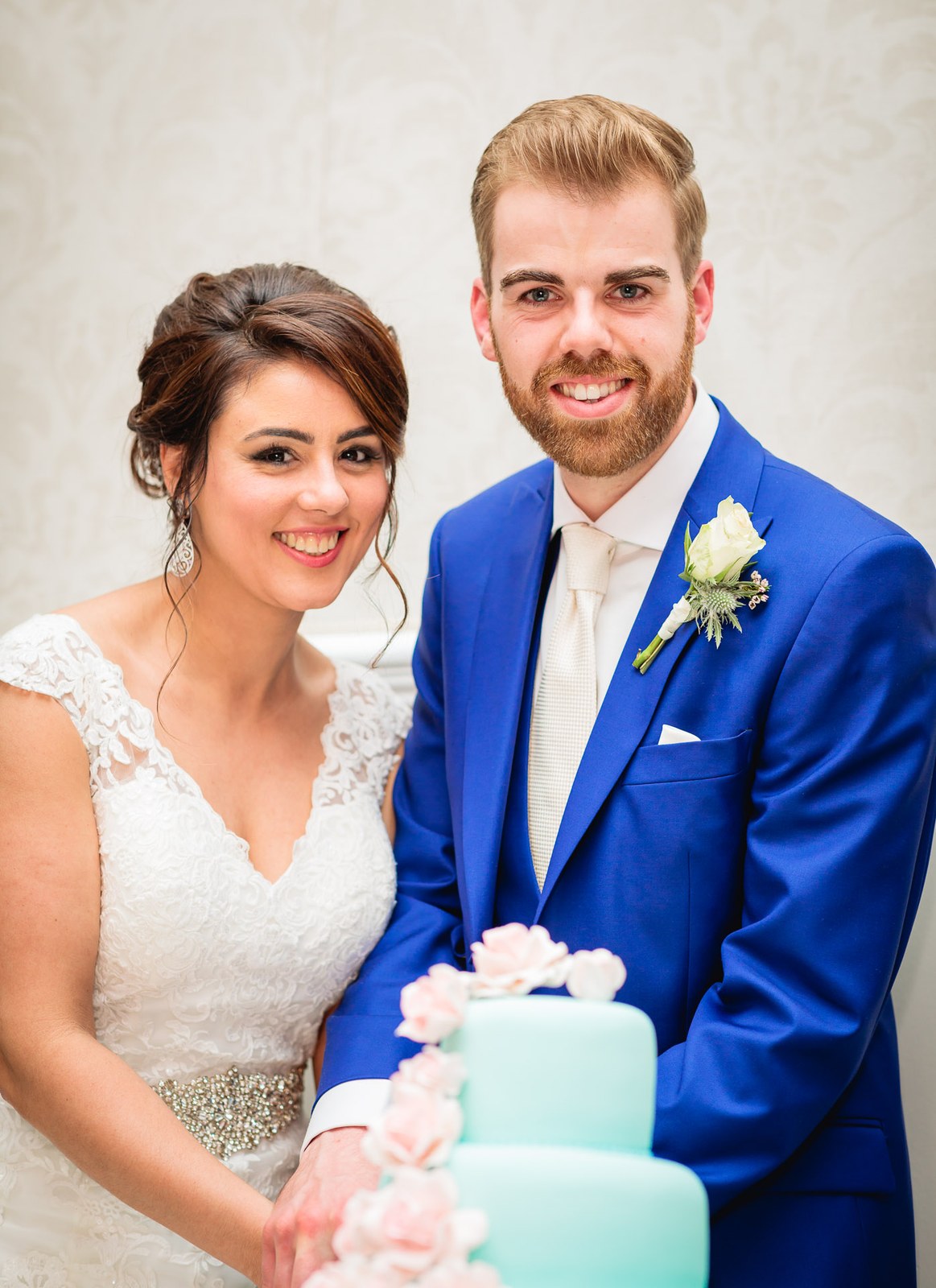 Bride and groom cutting their mint green tiered cake trimmed with pink roses