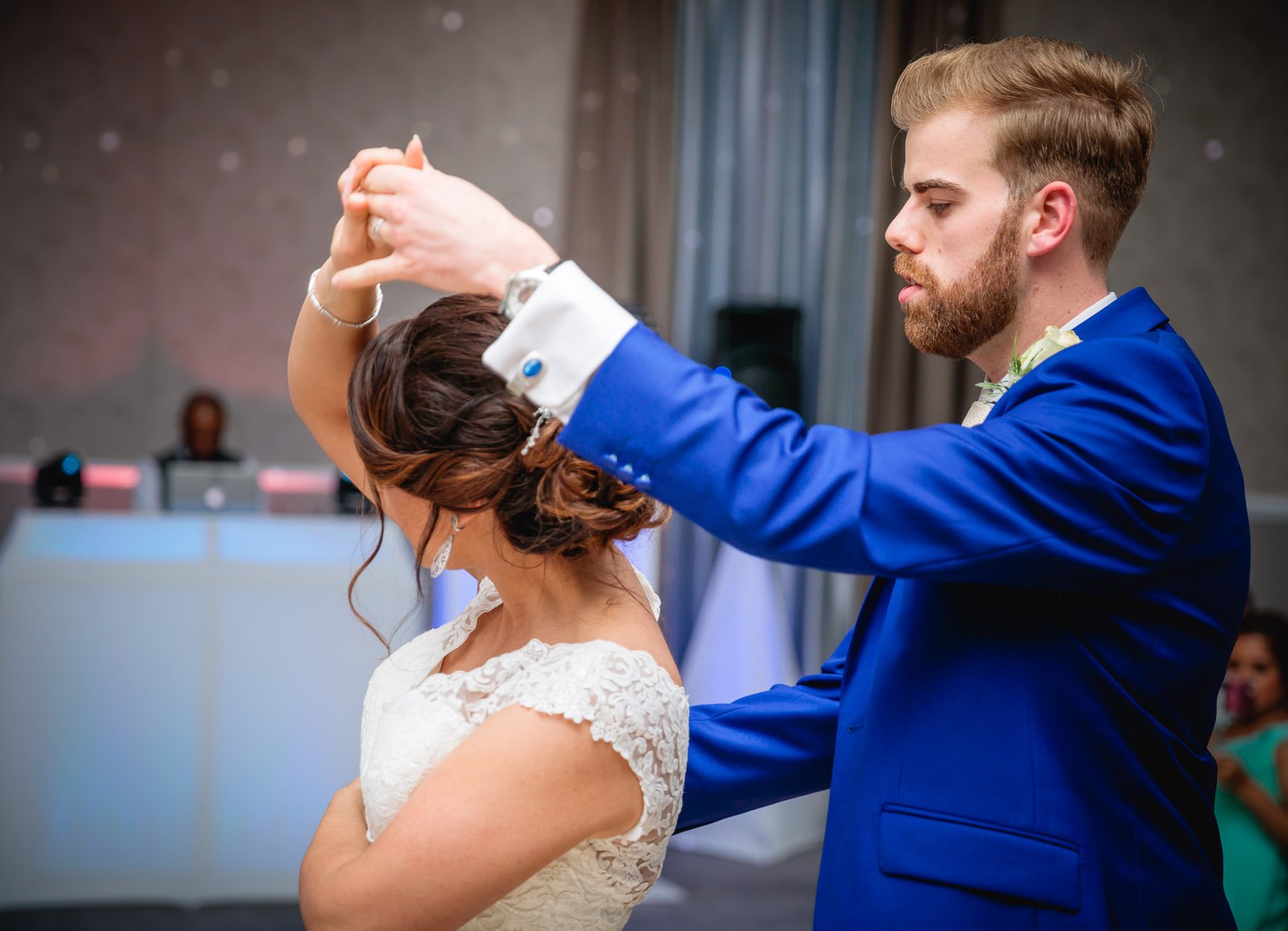 The groom twirling the bride during their first dance by the DJ booth