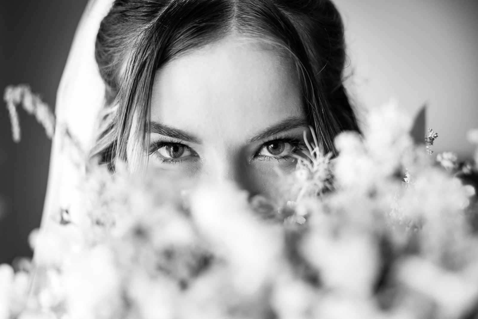 Black and white close-up of the bride's eyes above sprigs of gypsophila