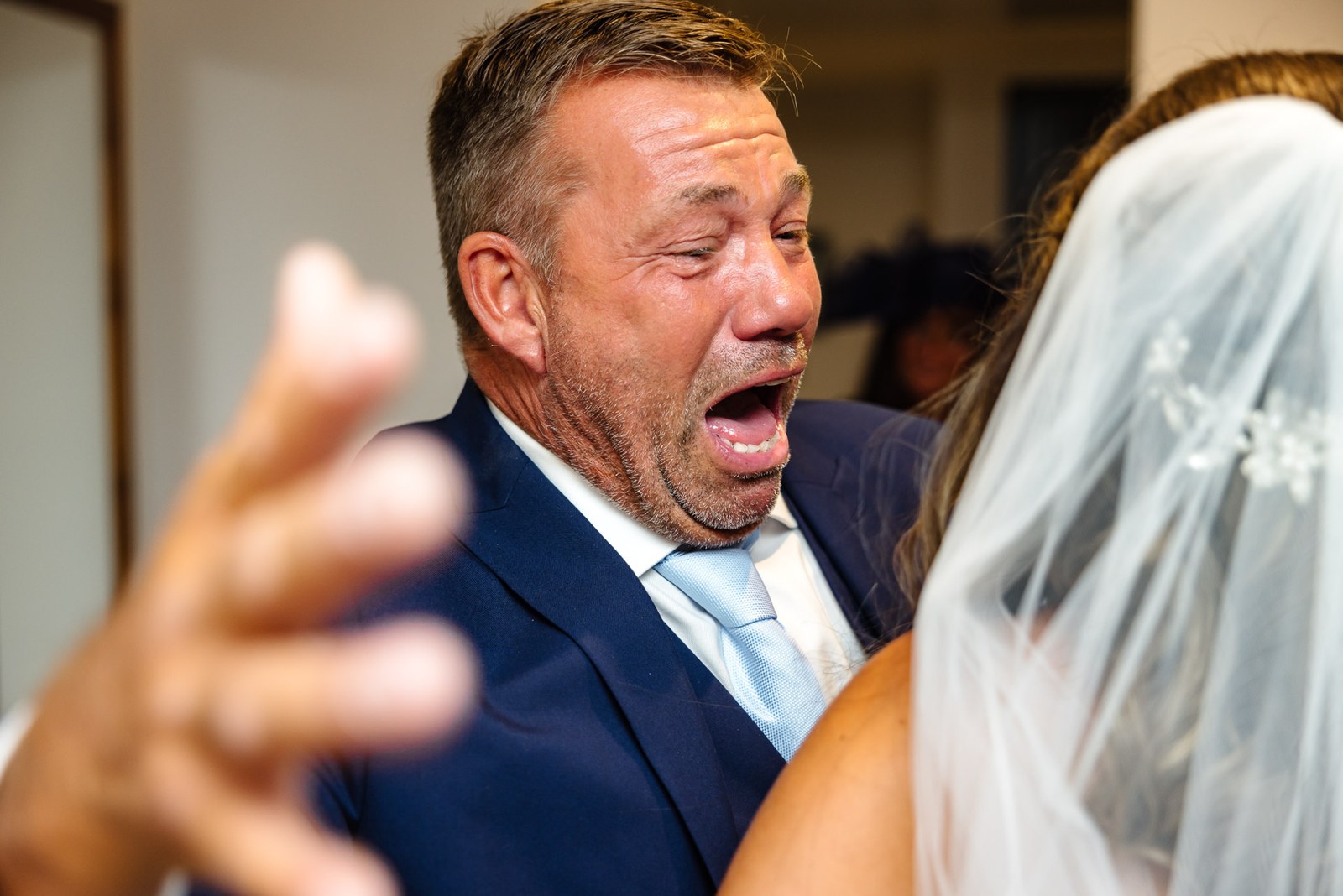 Emotional father in a navy suit overcome as he sees his daughter