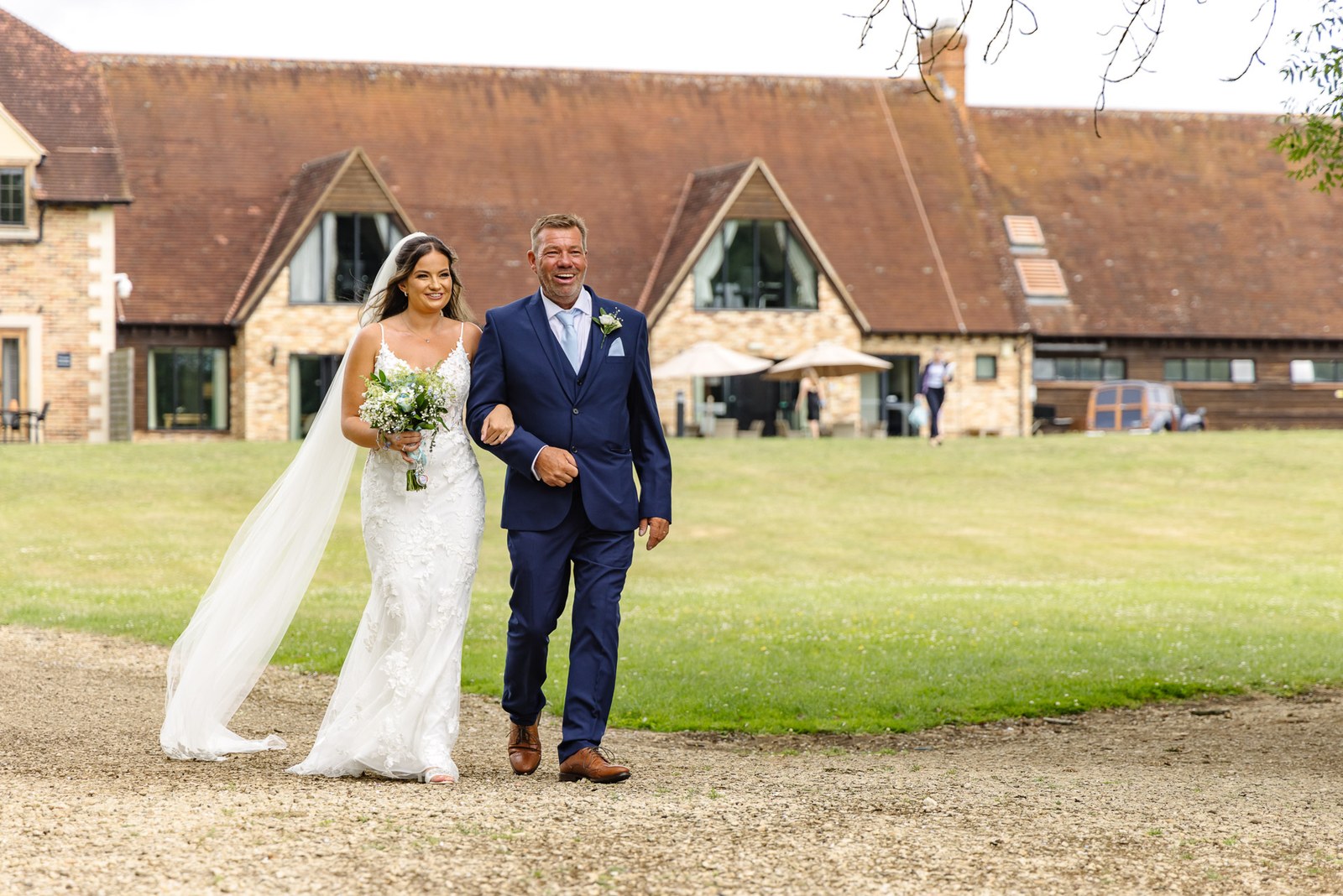 Bride walking through the grounds of voco Oxford Thames on her father's arm