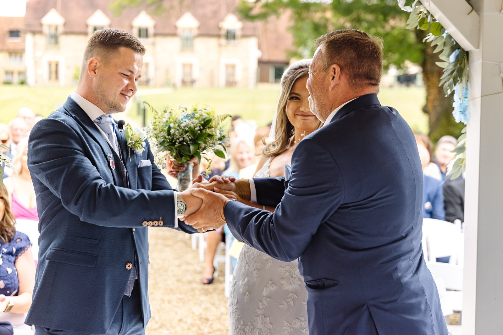 Father giving the bride away to the groom at the voco Oxford Thames ceremony pavilion