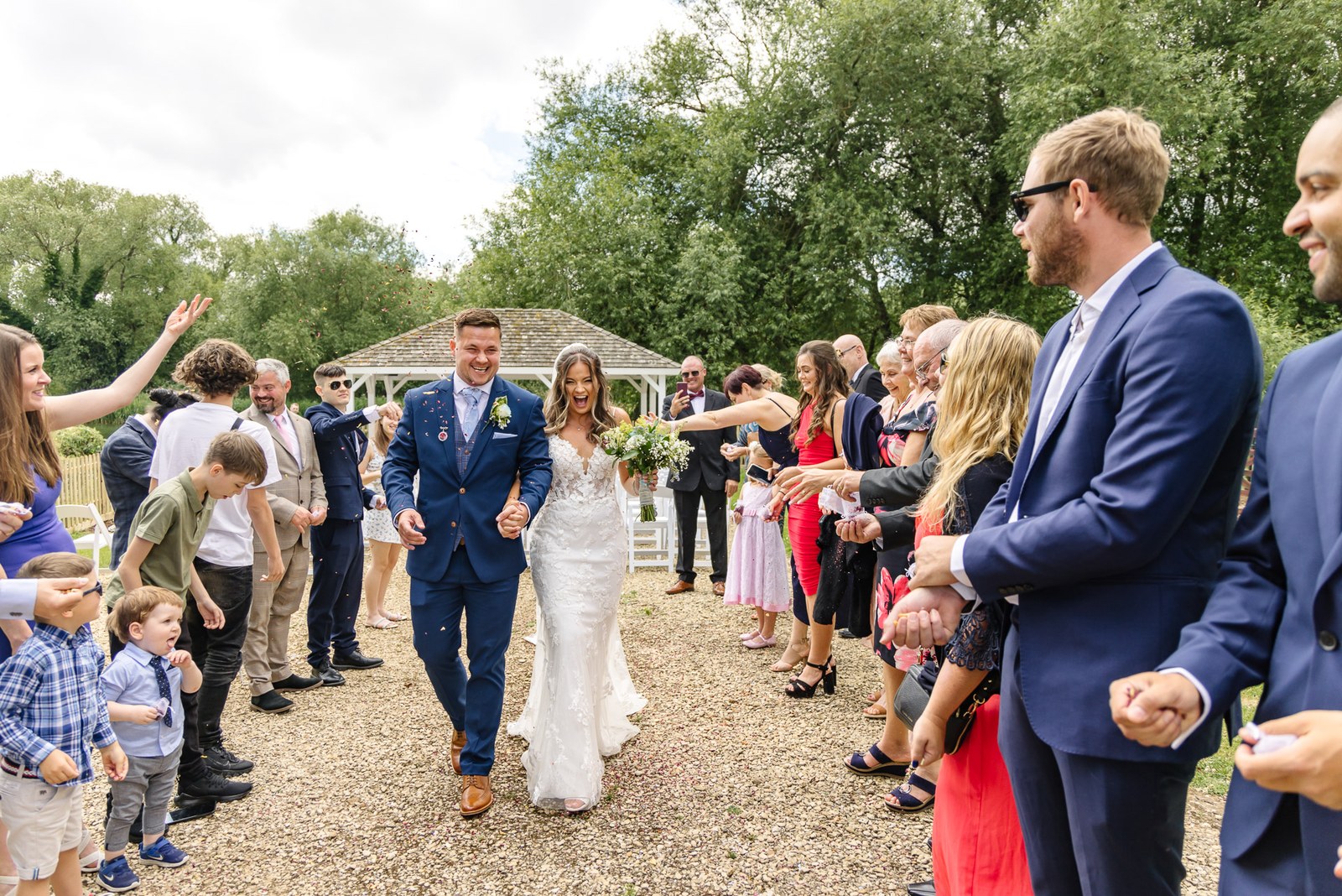 Newlyweds walking back down the aisle at voco Oxford Thames as guests cheer