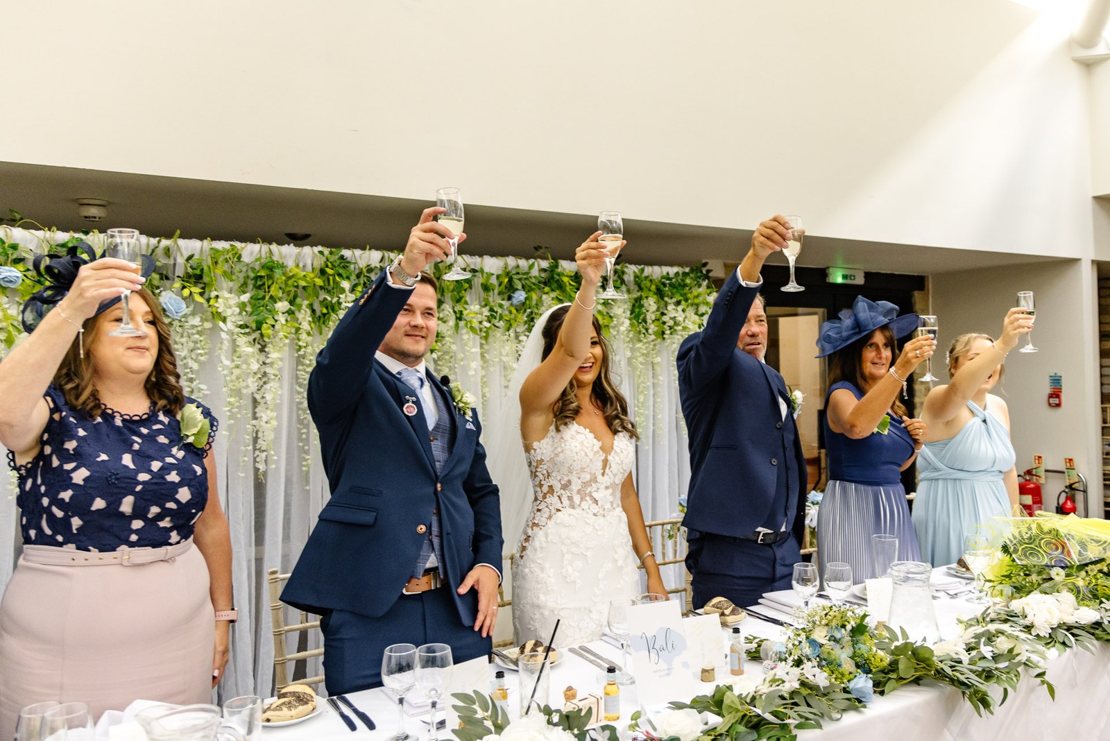 Bride and groom raising their glasses for a toast at the top table