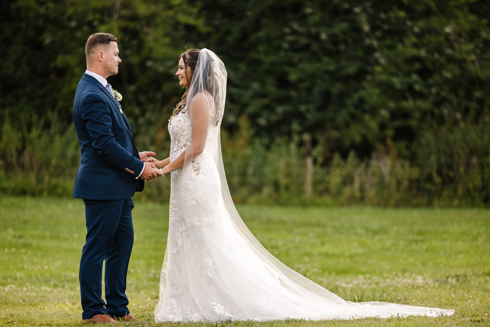 The couple holding hands and gazing at each other on the lawn