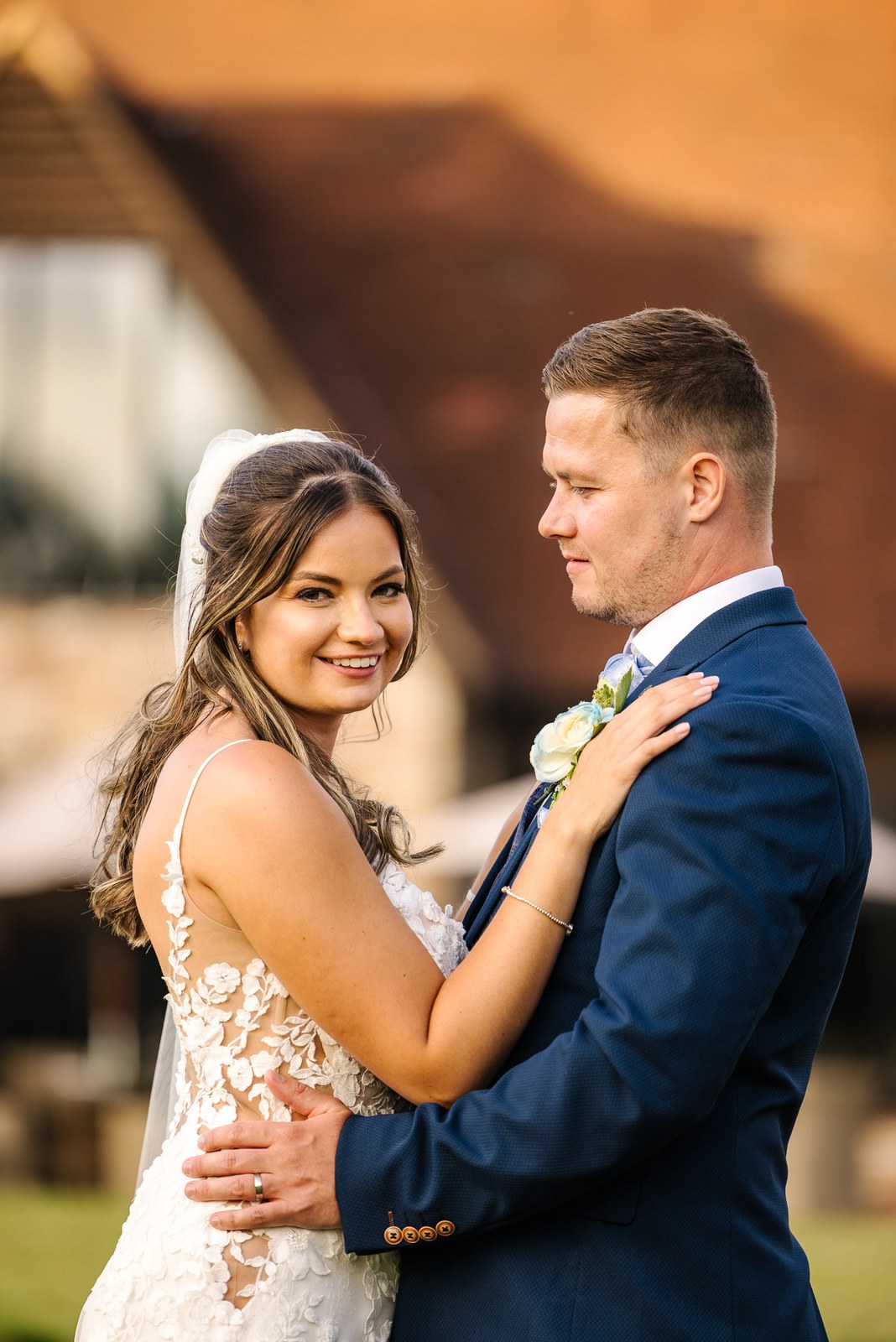 Bride smiling over her shoulder while embracing the groom outside the hotel