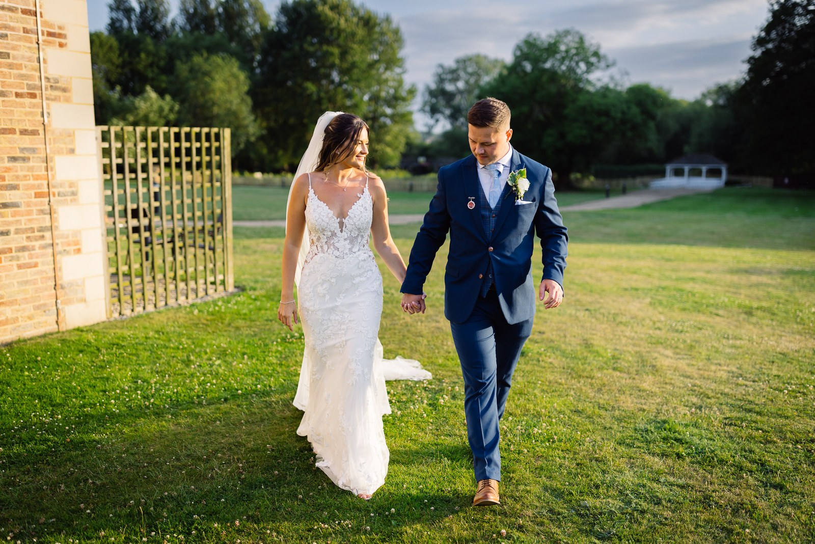 The couple walking across the grounds of voco Oxford Thames at dusk