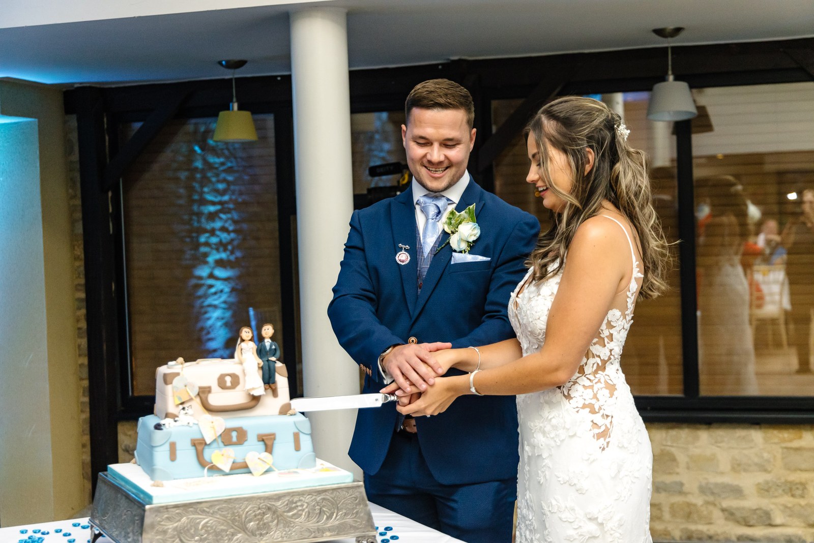 The couple cutting their suitcase-themed wedding cake together