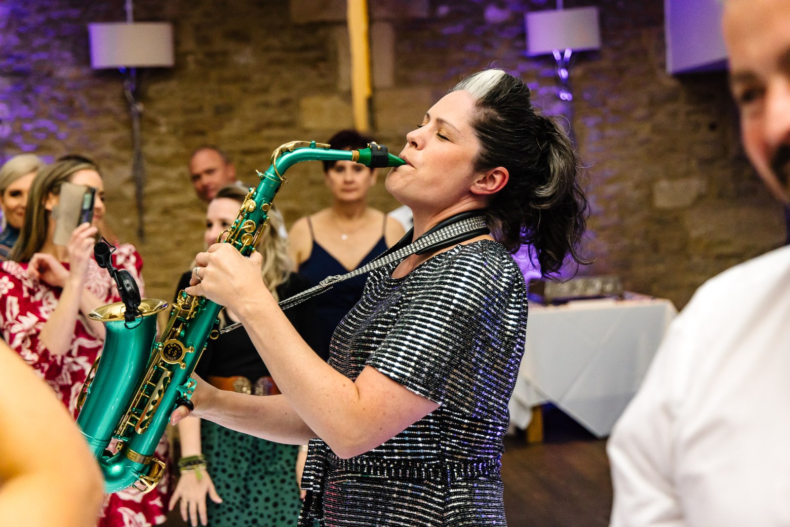 Saxophonist performing among the guests on the dance floor