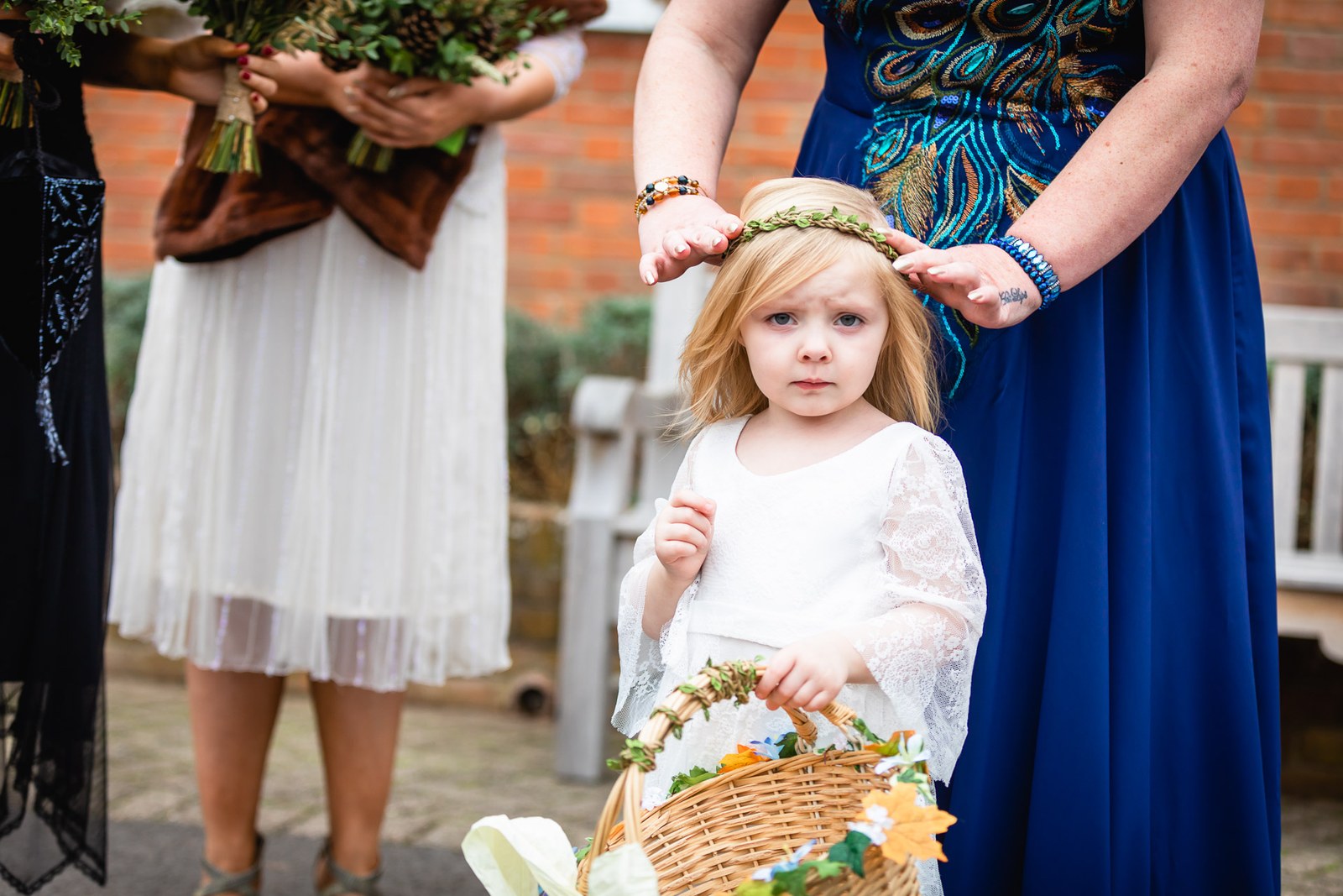 A flower girl having a floral crown placed on her head, petal basket in hand