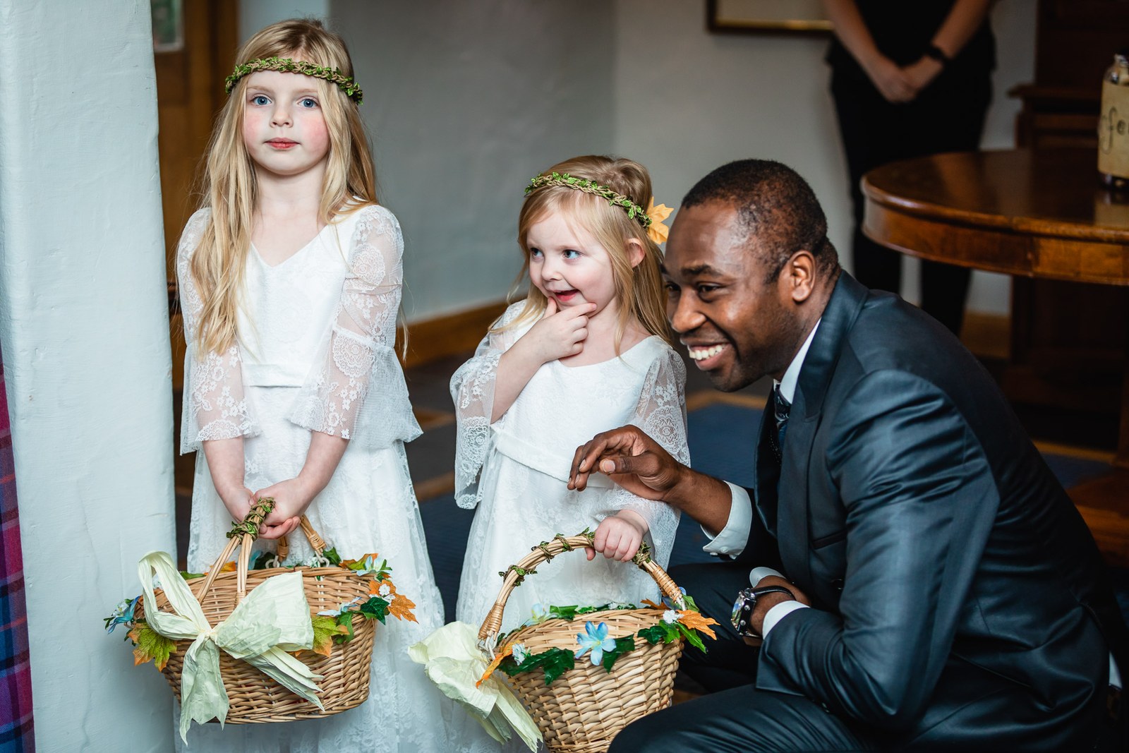 Two young flower girls with floral crowns and petal baskets before the ceremony
