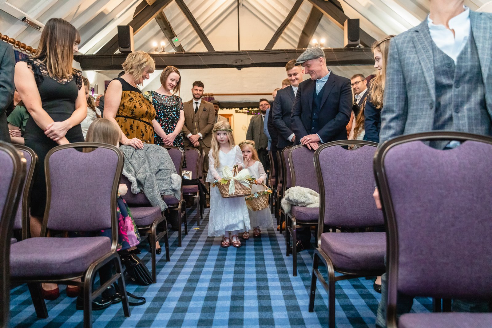 Flower girls carrying petals down the aisle in the beamed ceremony room at Windmill Village Hotel