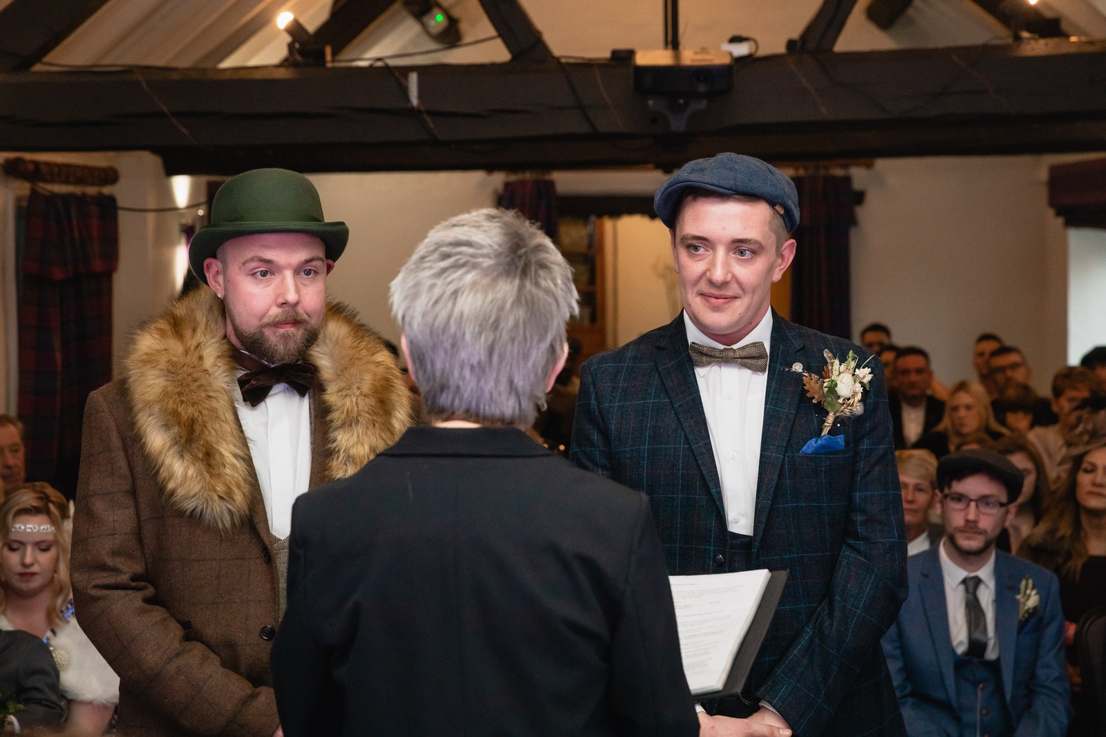 The two grooms facing the registrar during their vintage-themed ceremony