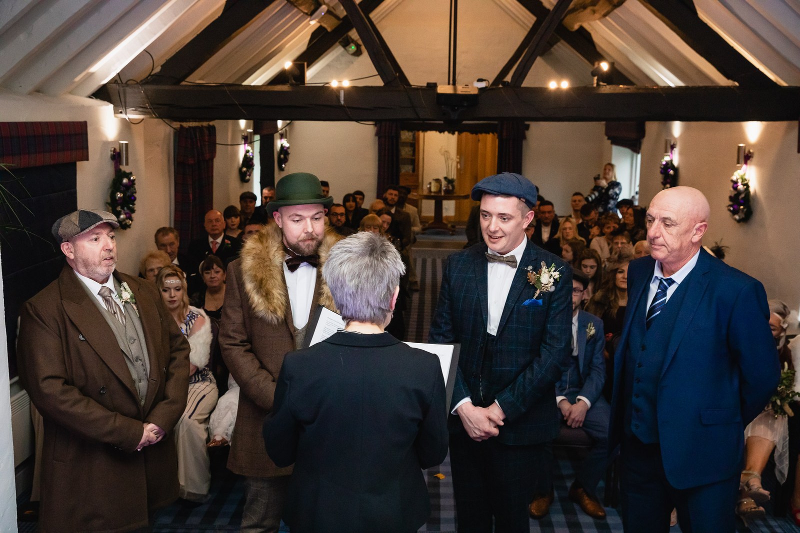 The grooms exchanging vows before the registrar as guests stand