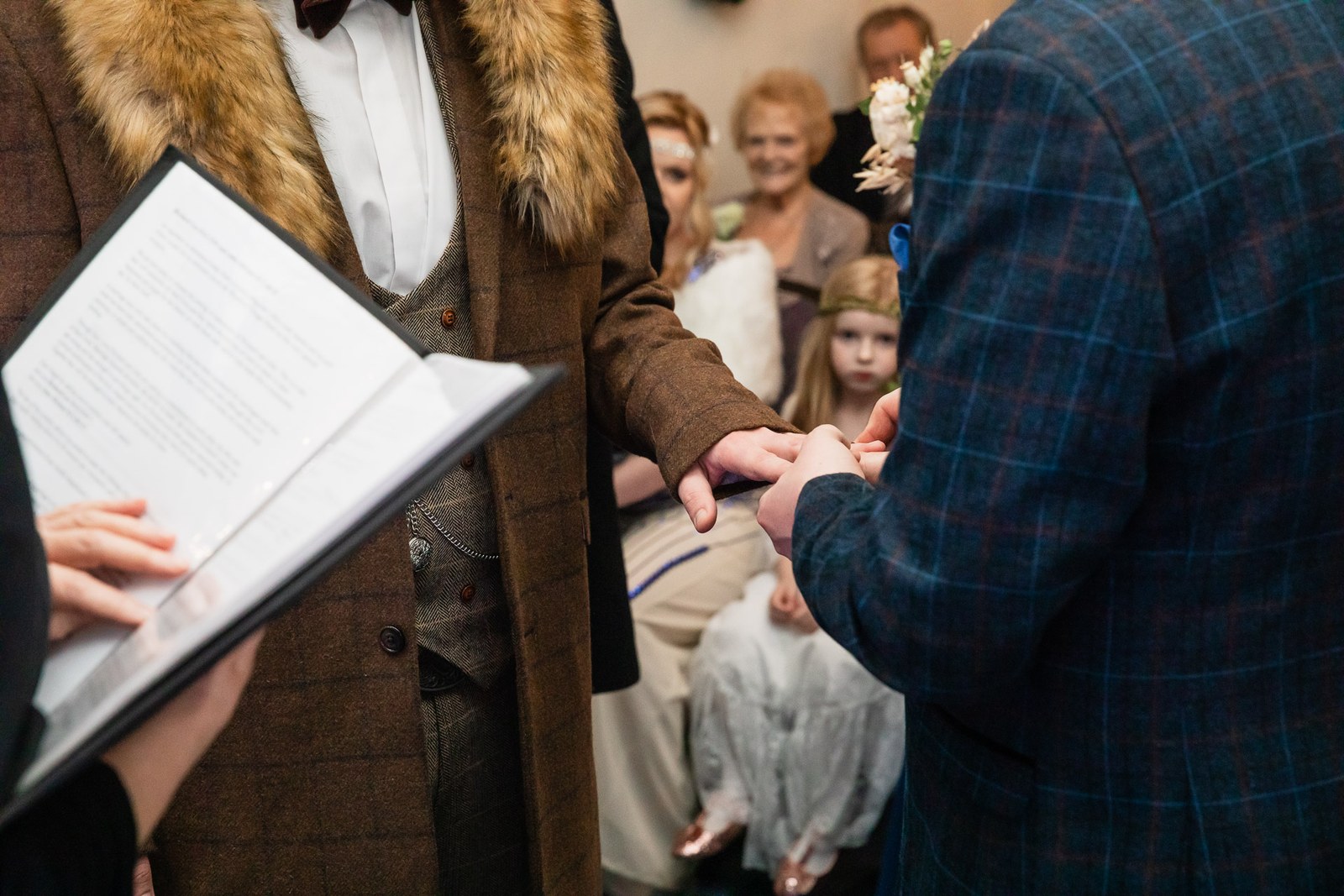 Close-up of hands during the ring exchange beside the order of service