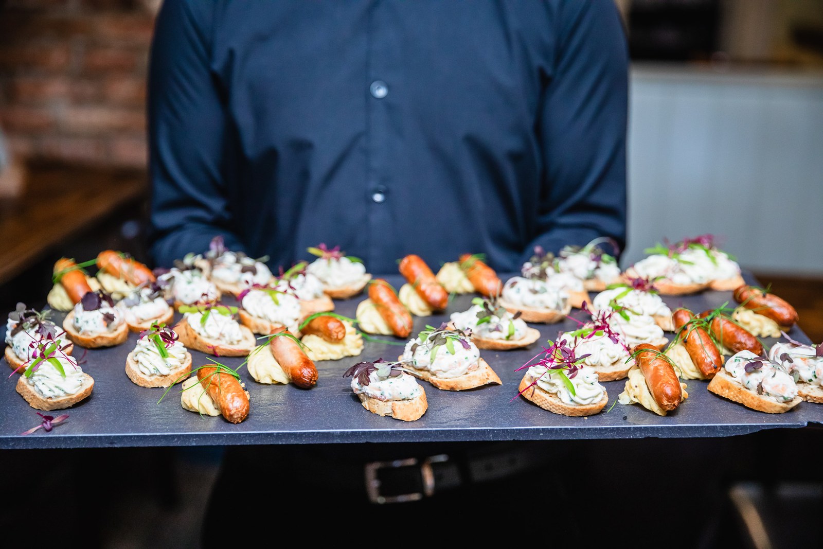 Waiter presenting canapes on a slate serving board