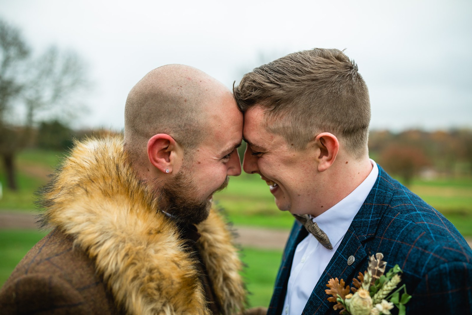 The grooms touching foreheads together among the autumn trees