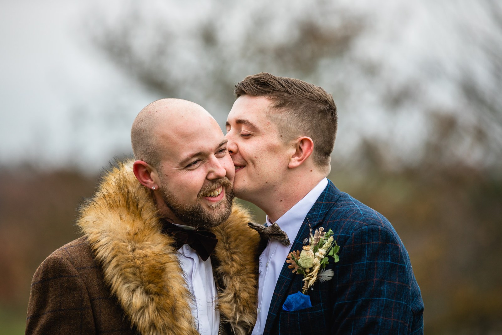 One groom kissing his partner on the cheek in the grounds