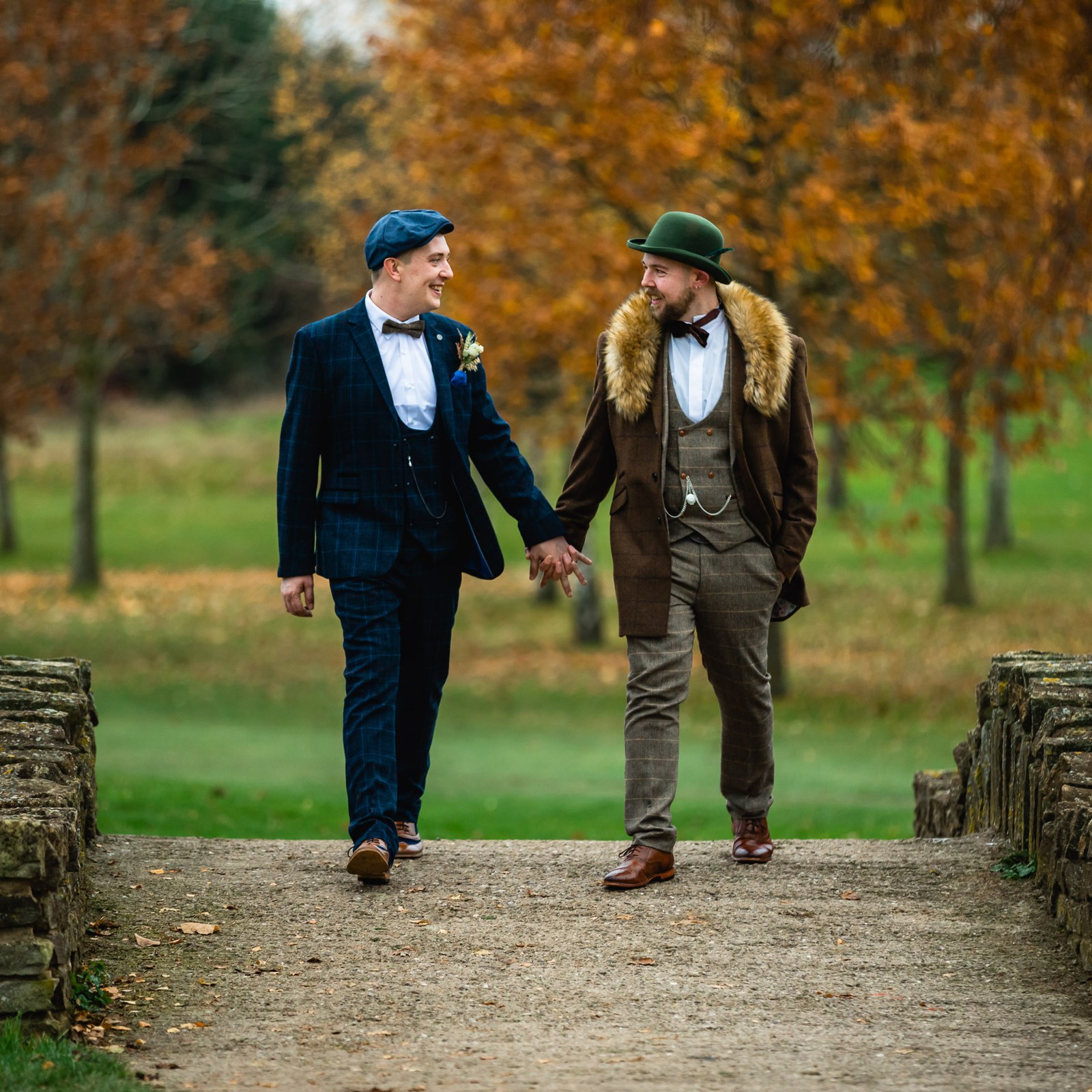 The couple walking a stone-walled path through the autumn grounds at Windmill Village Hotel