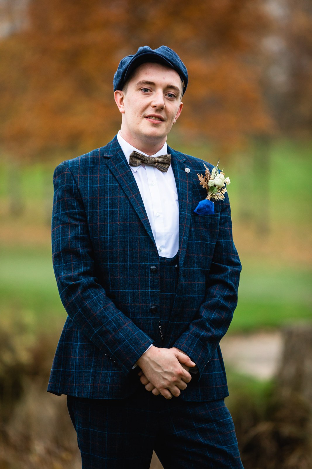 Portrait of a groom in a checked navy suit, flat cap and buttonhole