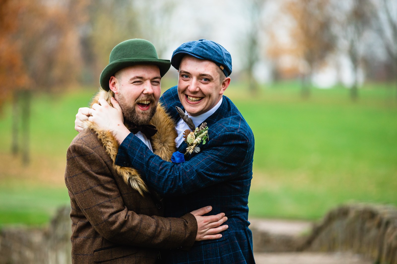 The two grooms laughing together in a close embrace outdoors