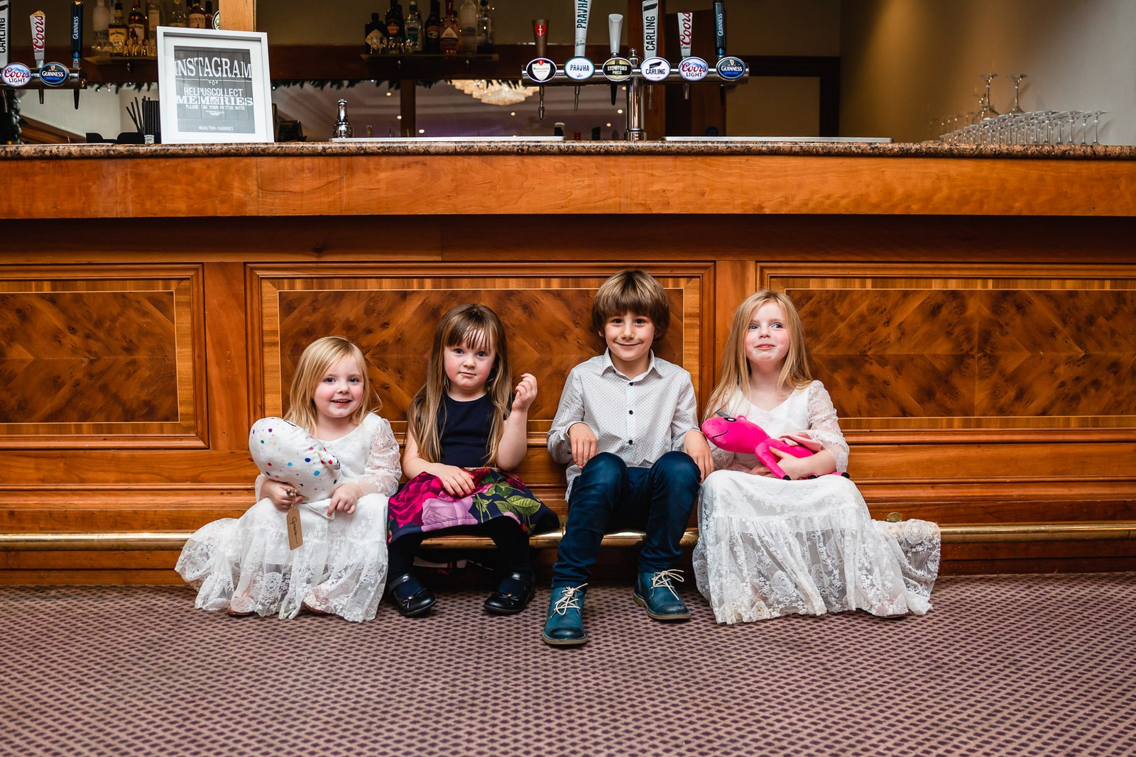 Young children sitting in a row in front of the wooden bar