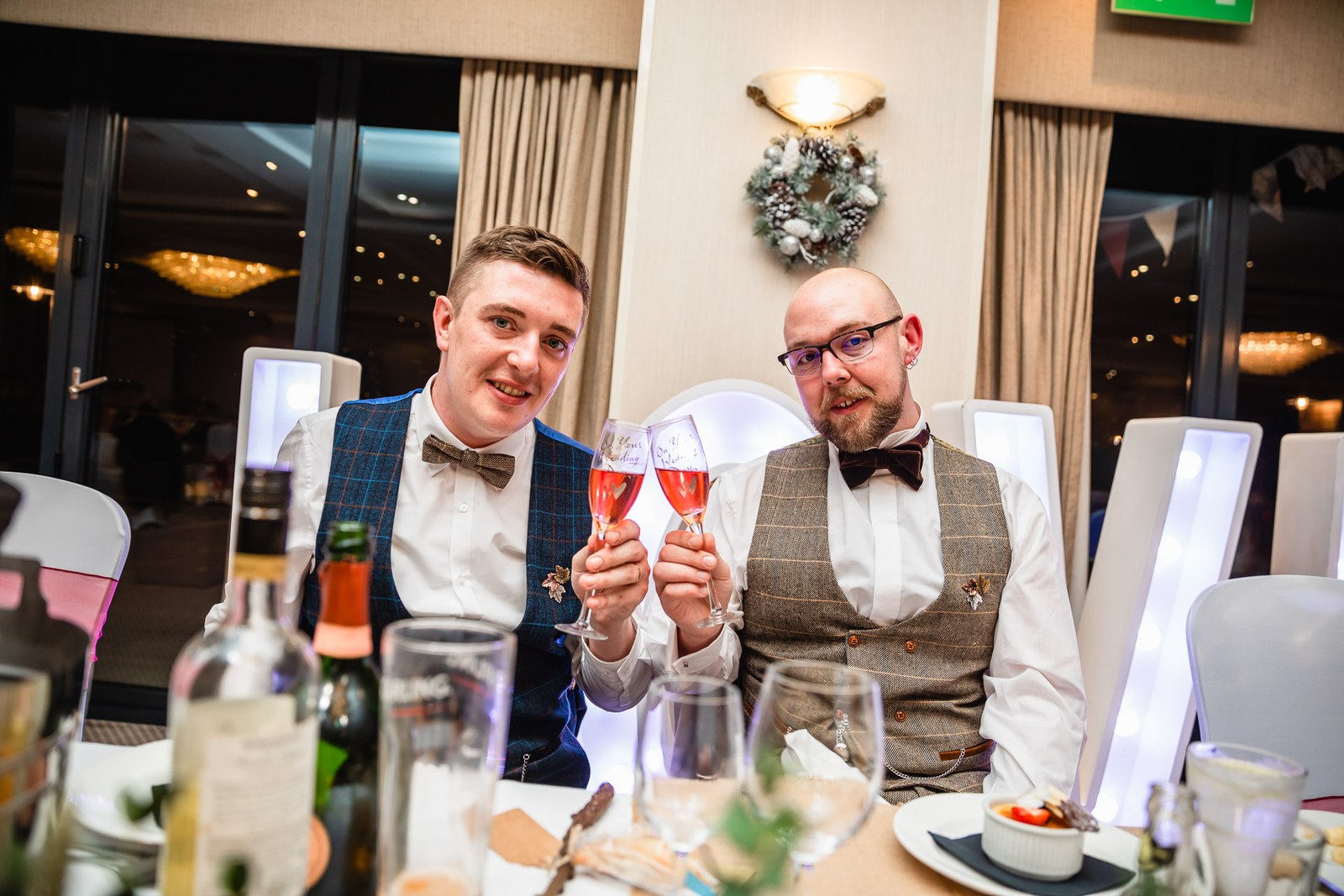 The two grooms raising a champagne toast at the top table