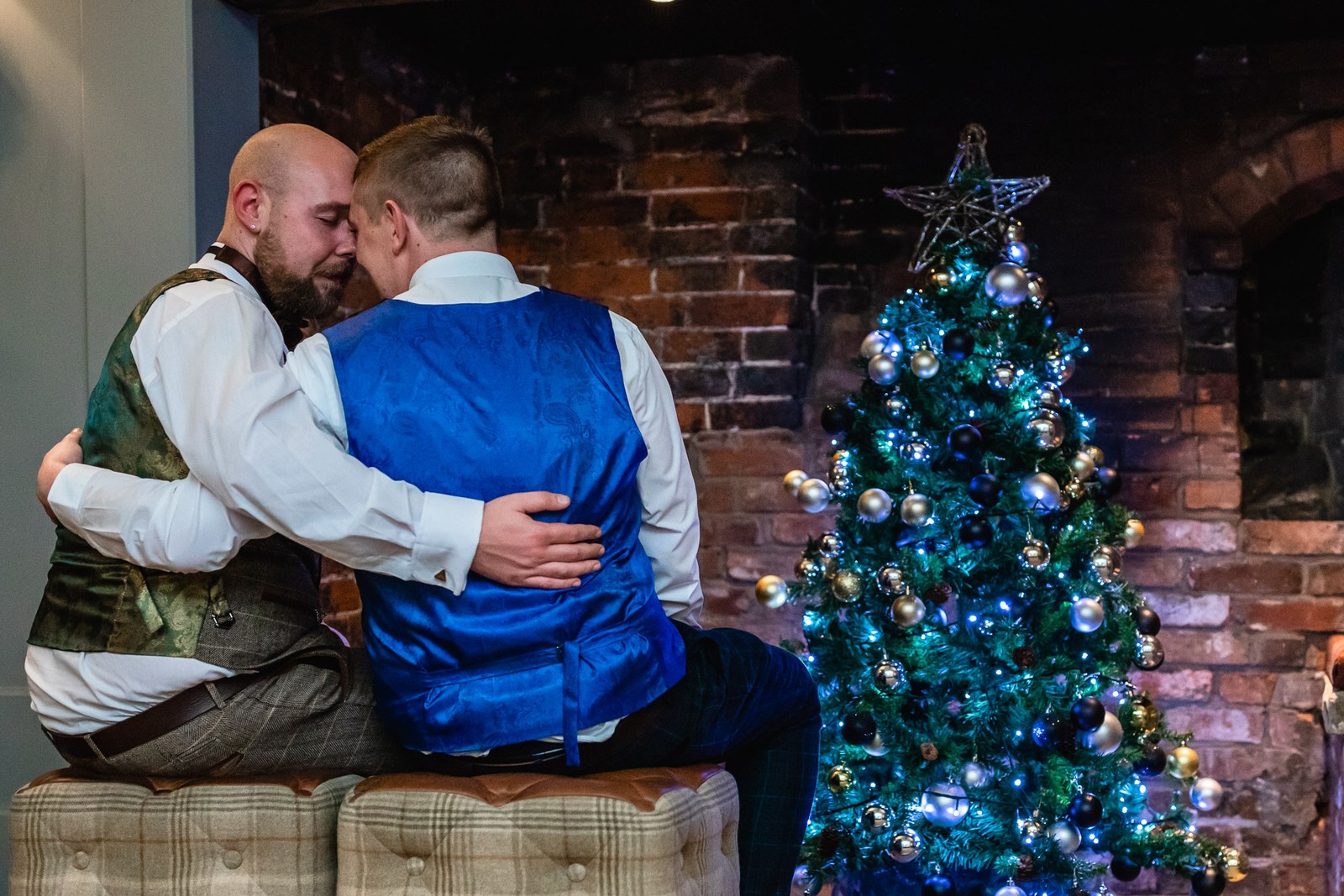 The two grooms embracing beside the Christmas tree