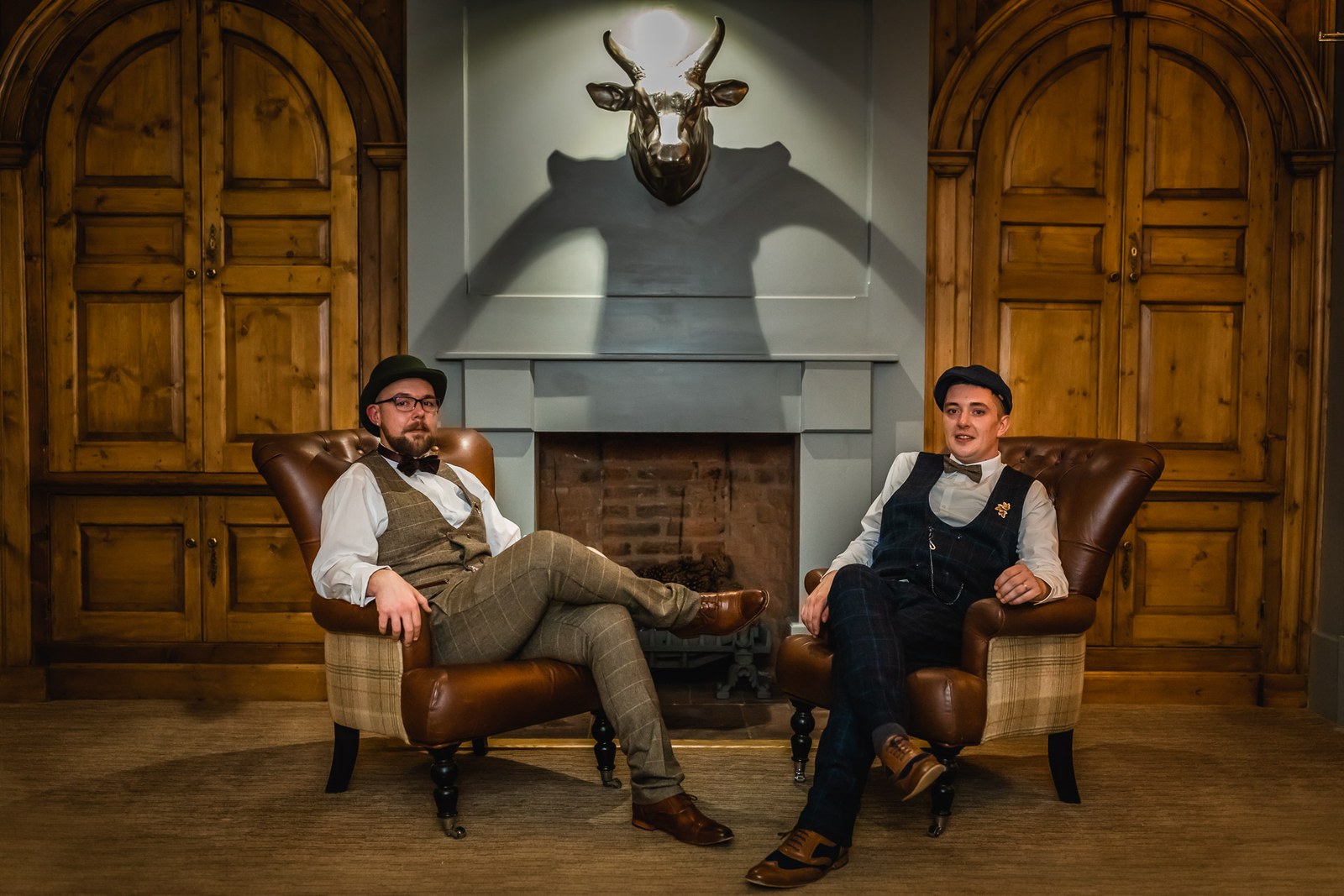 The grooms relaxing in leather armchairs by the fireside at Windmill Village Hotel