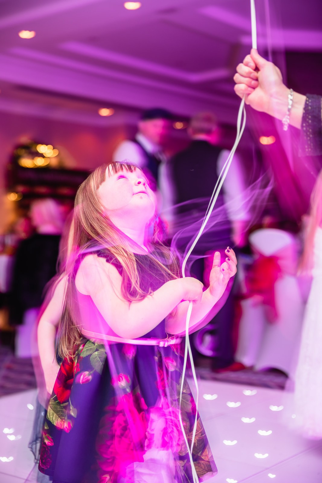 A young guest playing with balloon ribbon on the dance floor