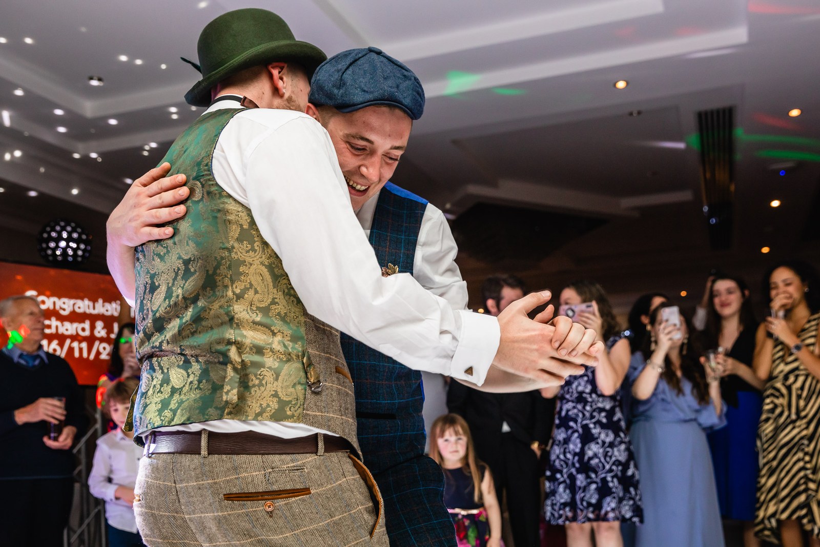 The grooms sharing their first dance as guests look on