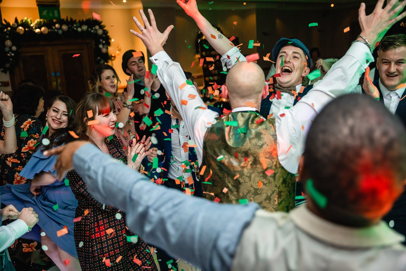Guests dancing with arms raised amid falling confetti