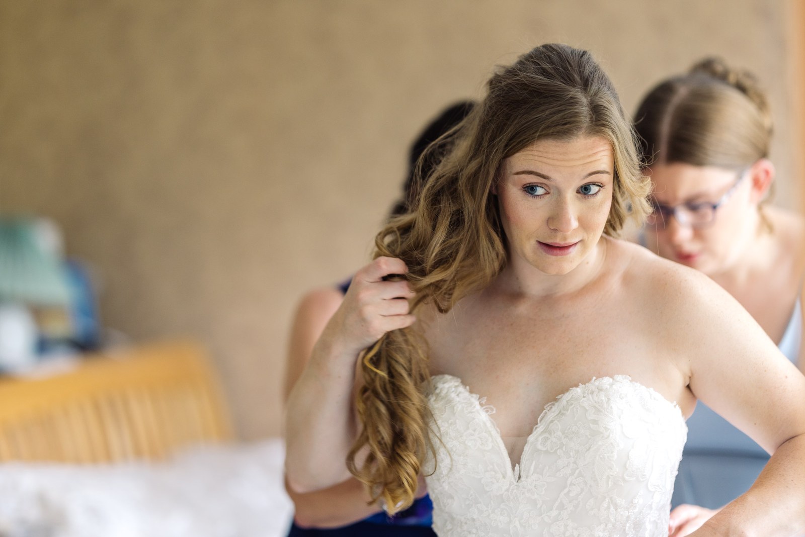 Bride having her hair styled while wearing her strapless lace gown