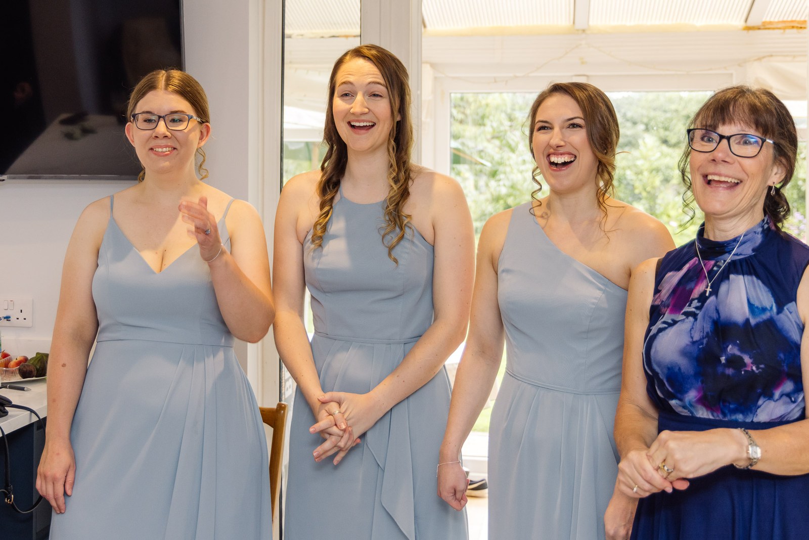 Bridesmaids in dusty-blue dresses laughing together before the ceremony