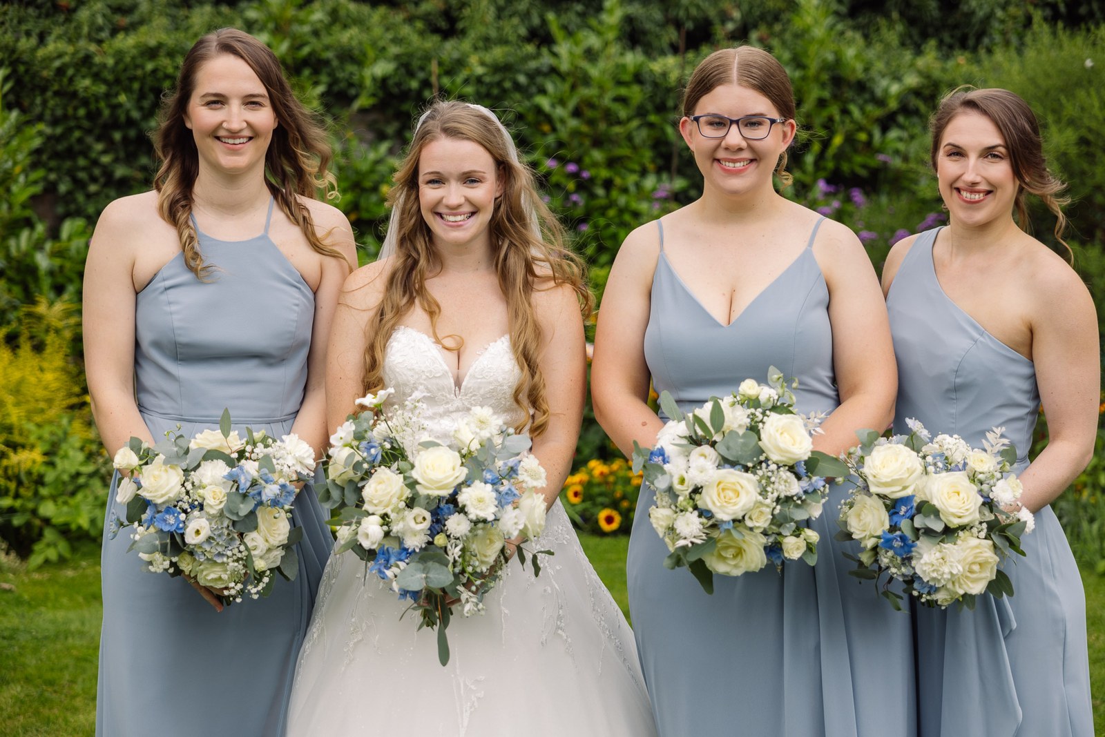 Bride and her bridesmaids with bouquets in the gardens at Winters Tale Country Barn