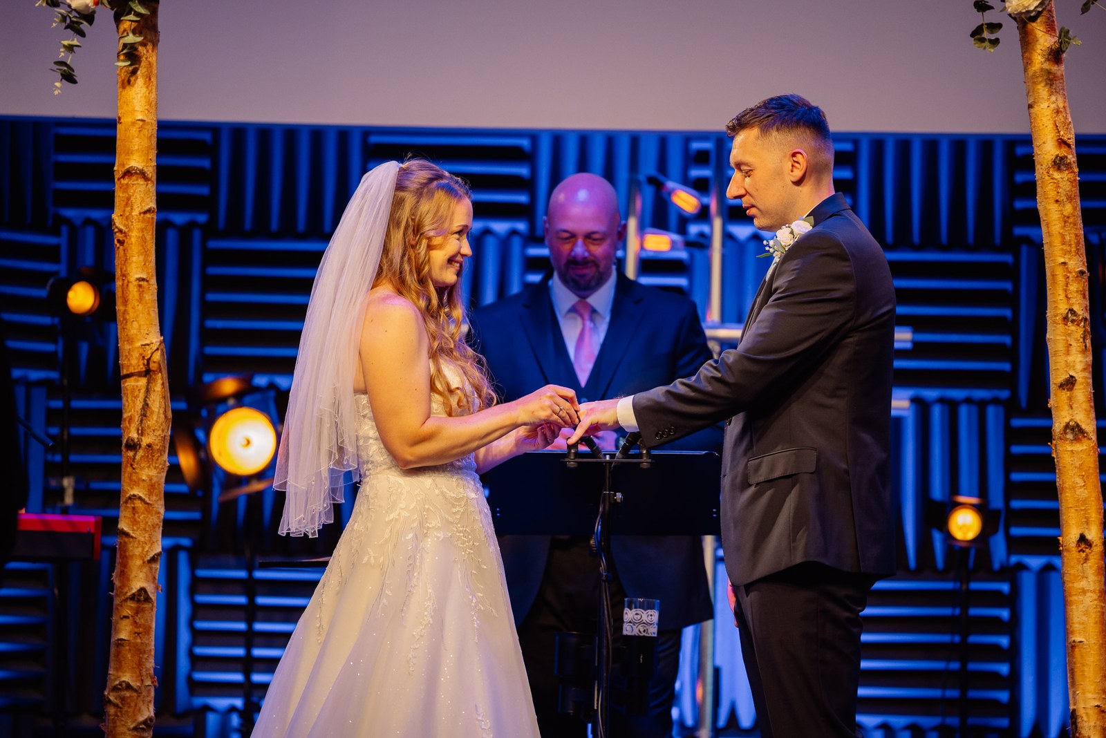 The couple exchanging rings beneath the decorated ceremony arch